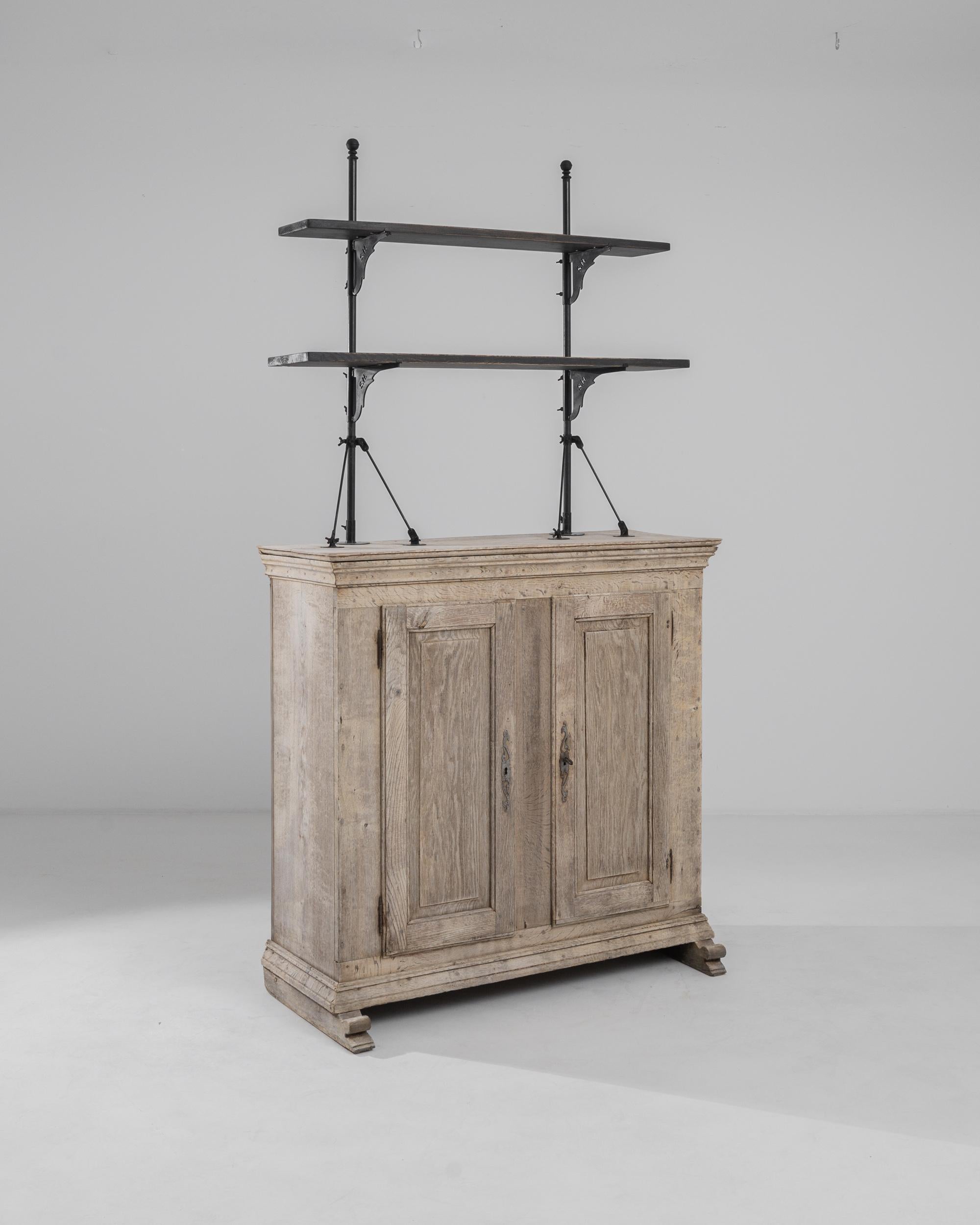 Made in France in the 19th century, this antique oak display cabinet offers a unique and practical silhouette. Two raised shelves are set upon slender metal posts to create an unobtrusive, pared-back open storage concept. The elegant shape of the