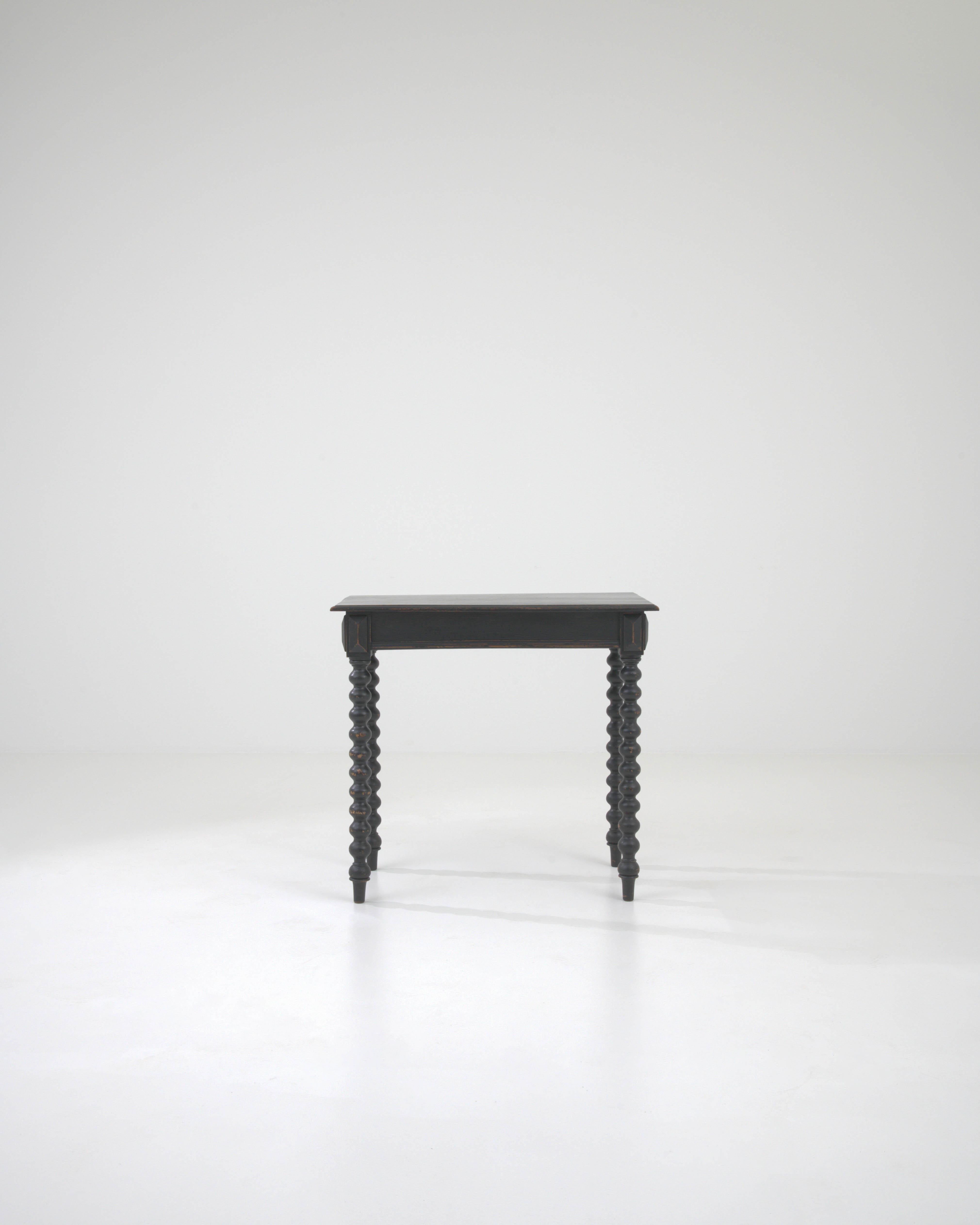This 19th Century French Wood Side Table exudes a subdued elegance with its deep black patina, a testament to its rich history and timeless appeal. The piece stands on delicately turned spindle legs, their spiraling forms a dance of shadows and