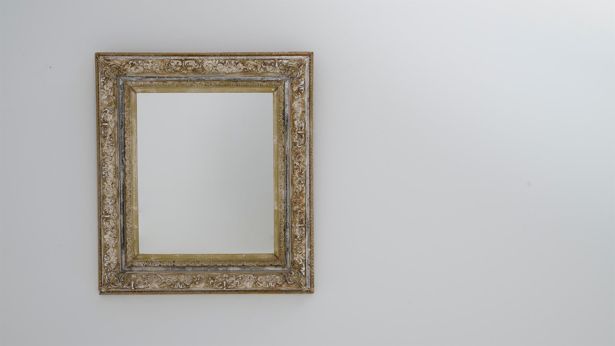 This 19th Century French mirror showcases a stunning wood frame with a deep patina, offering a beautiful blend of rustic charm and antique sophistication. The intricately detailed carvings on the frame are highlighted by a weathered finish,