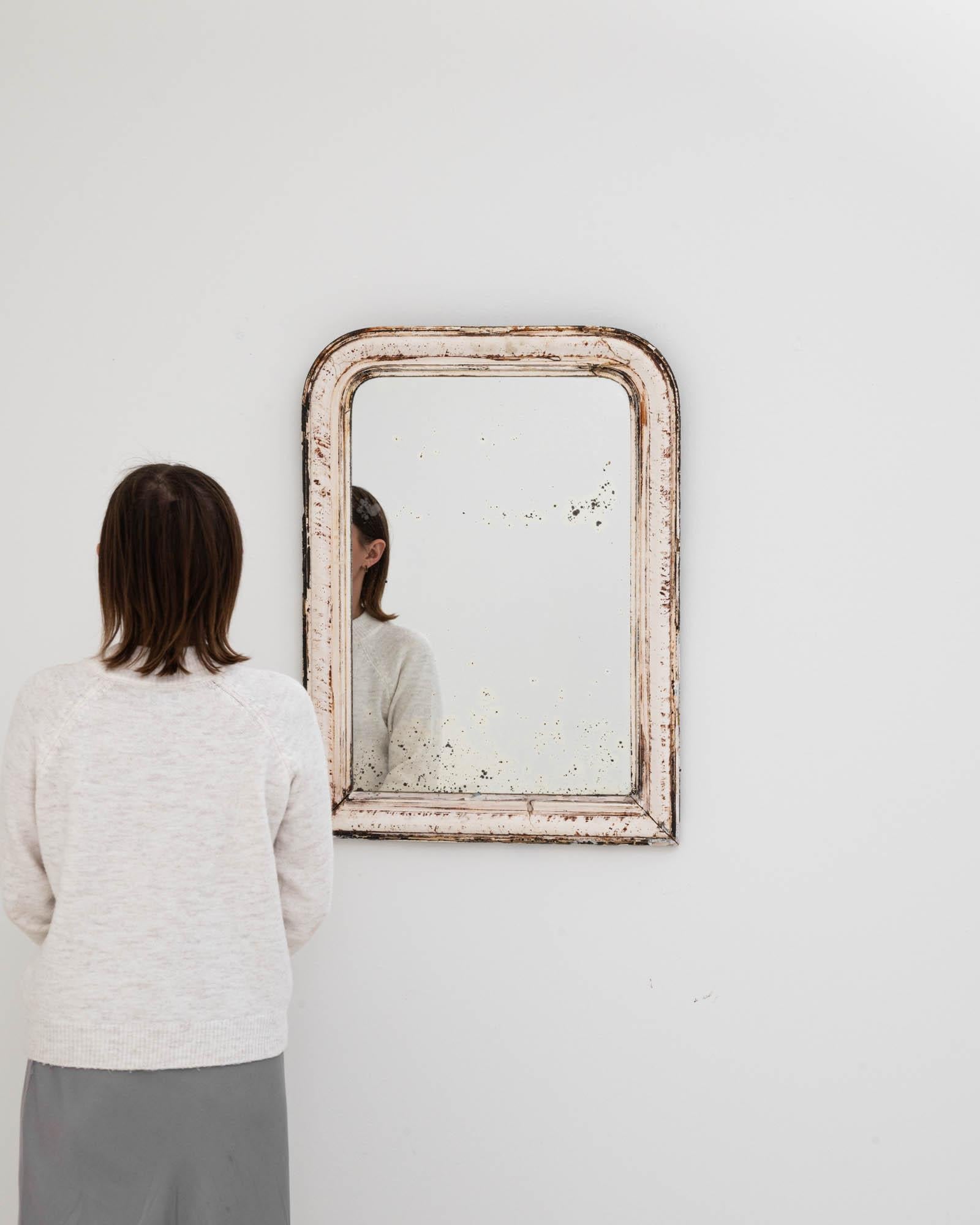 Embrace the rustic elegance of a bygone era with this enchanting 19th Century French Wood Patinated Mirror. Its distressed white finish and natural wood showing through tell a story of age and character, bringing a piece of French history into your
