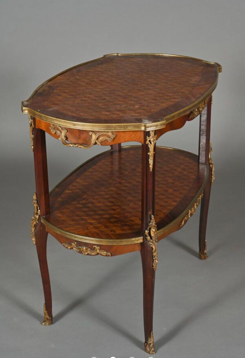 19th Century wood veneer side table, the curved top and spandrel shelf with bottomless cube marquetry, curved uprights and chased and gilded bronze ornamentation such as lingotière, side handles, falls and sabots. Louis XV style H. 78.5 - W. 80.5 -