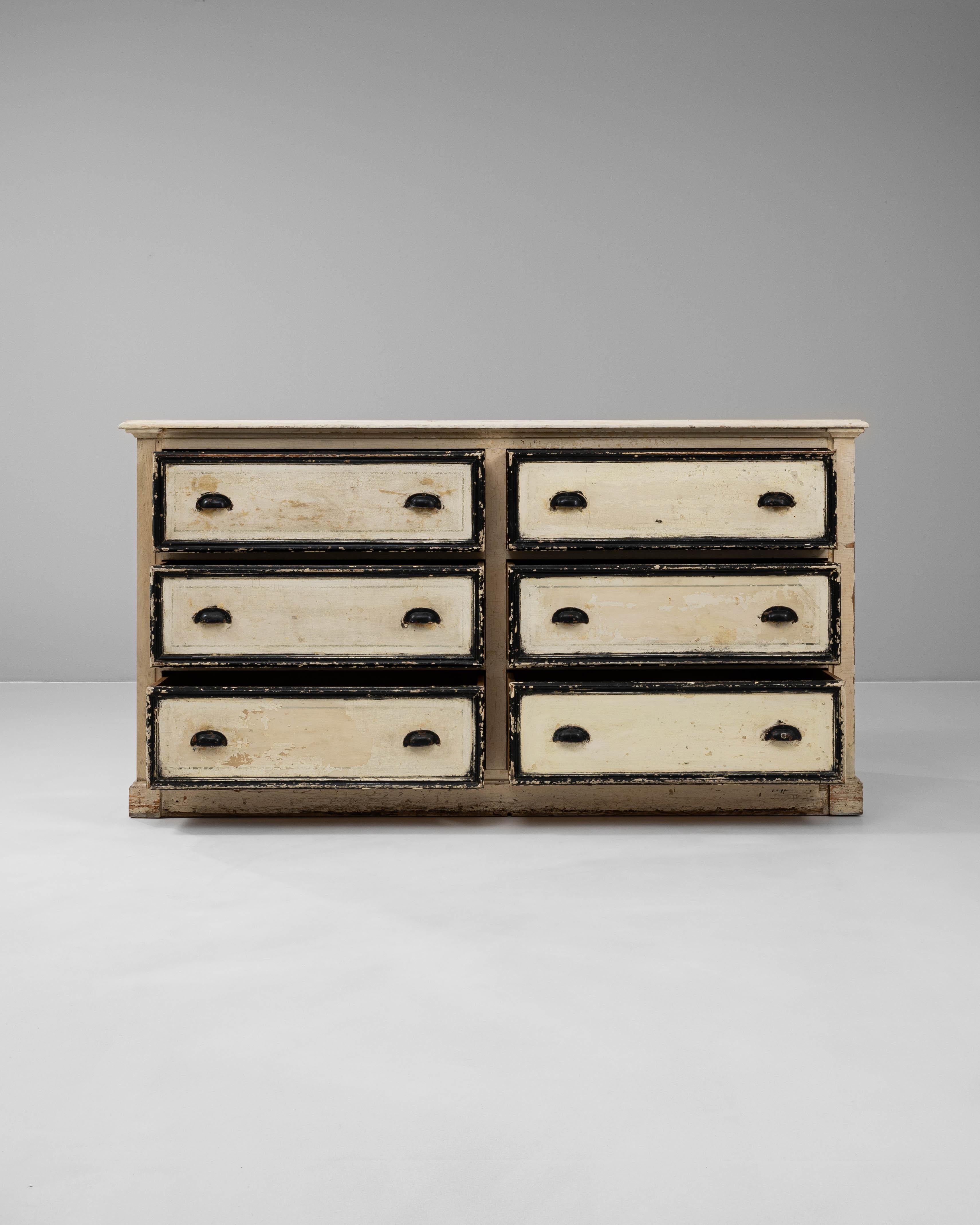Questa cassettiera francese in legno bianco patinato del XIX secolo emana un fascino vintage e senza tempo. Realizzato in legno massiccio, è caratterizzato da una patina bianca splendidamente affilata e da finiture nere a contrasto, che creano un