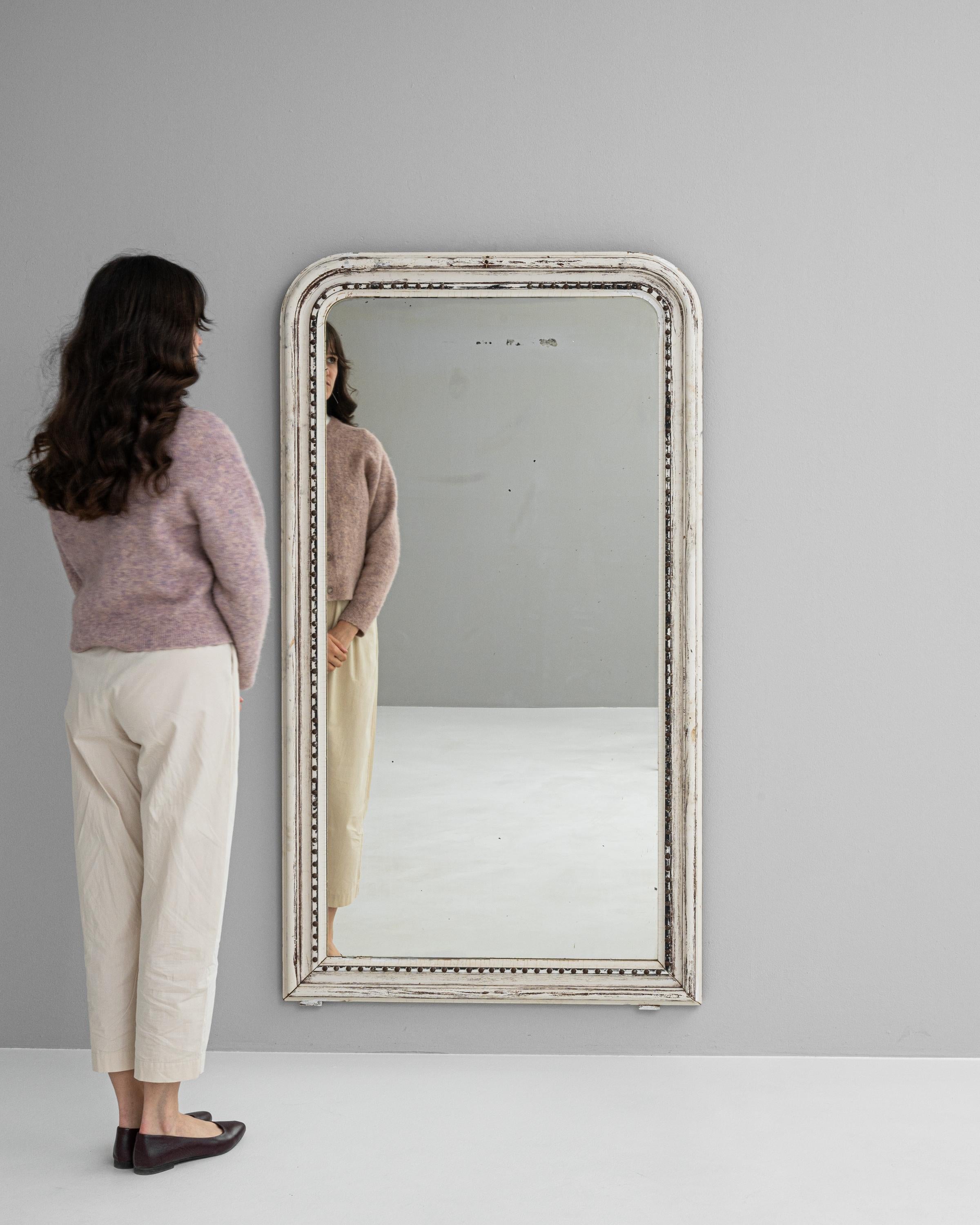 Versetzen Sie sich mit der Eleganz unseres weiß patinierten Spiegels aus französischem Holz des 19. Jahrhunderts in die Vergangenheit zurück - ein wahres Schmuckstück für jedes Zuhause. Dieser exquisite Spiegel wurde in einer Zeit gefertigt, in der