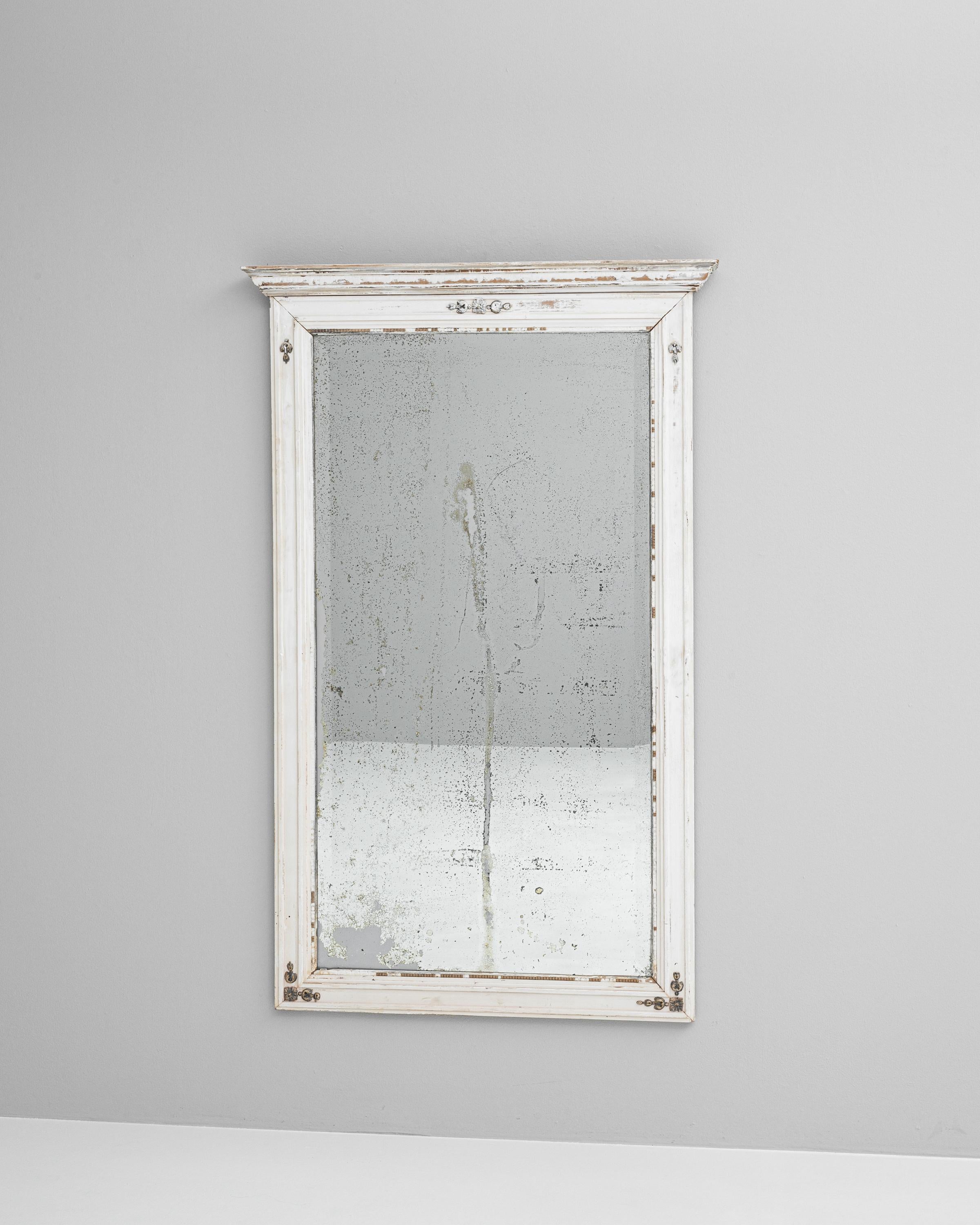 Presenting our exquisite 19th Century French Wood White Patinated Mirror, a treasured relic that exudes vintage charm and character. This mirror is framed in time-worn wood with a creamy white patina, artfully distressed to highlight the beauty of