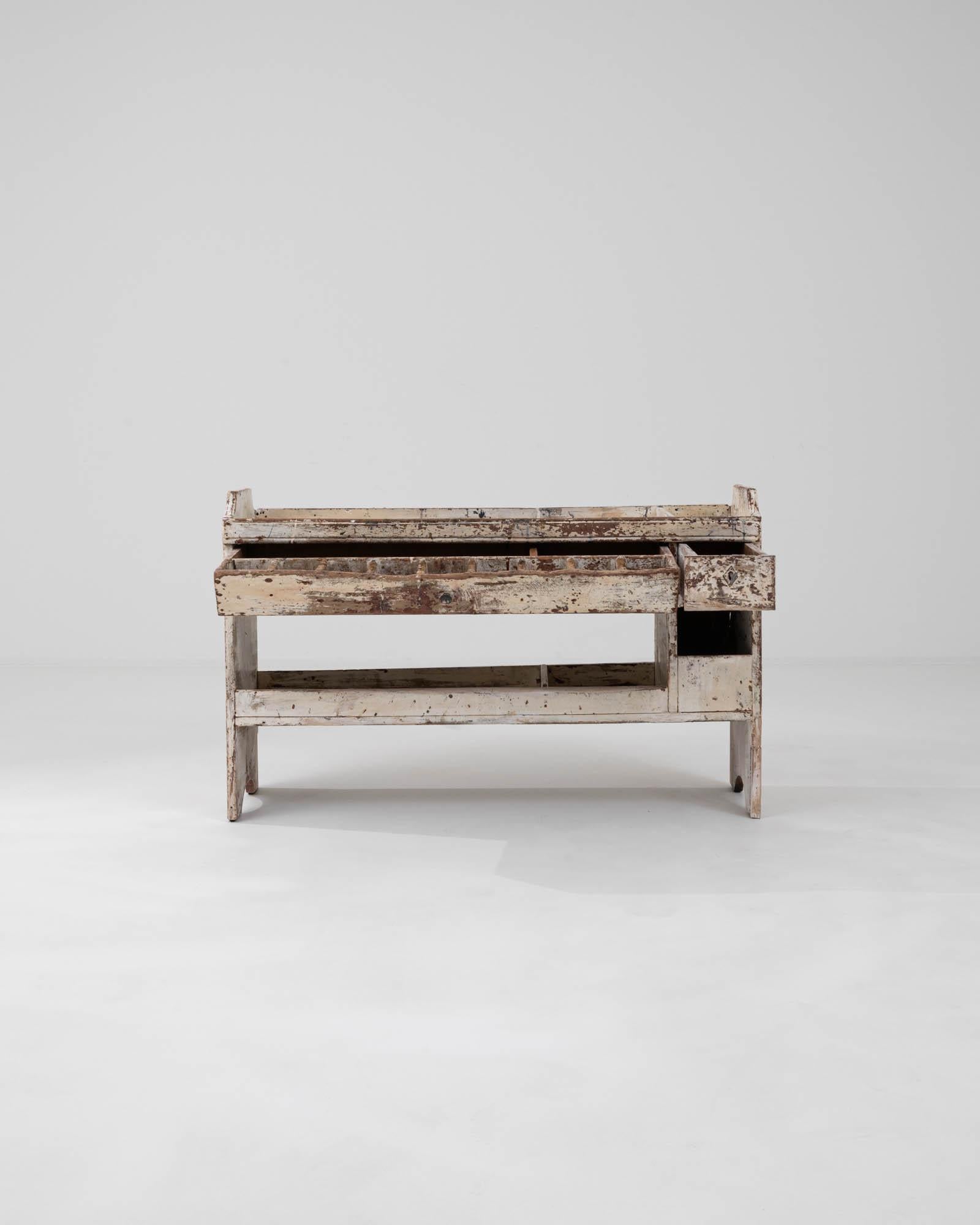 This 19th Century French Wood White Patinated Shelf exudes a rich sense of history through its lovingly worn white finish. Each layer of chipped paint and wood reveals stories of its past, adding depth and character to this unique piece. Designed