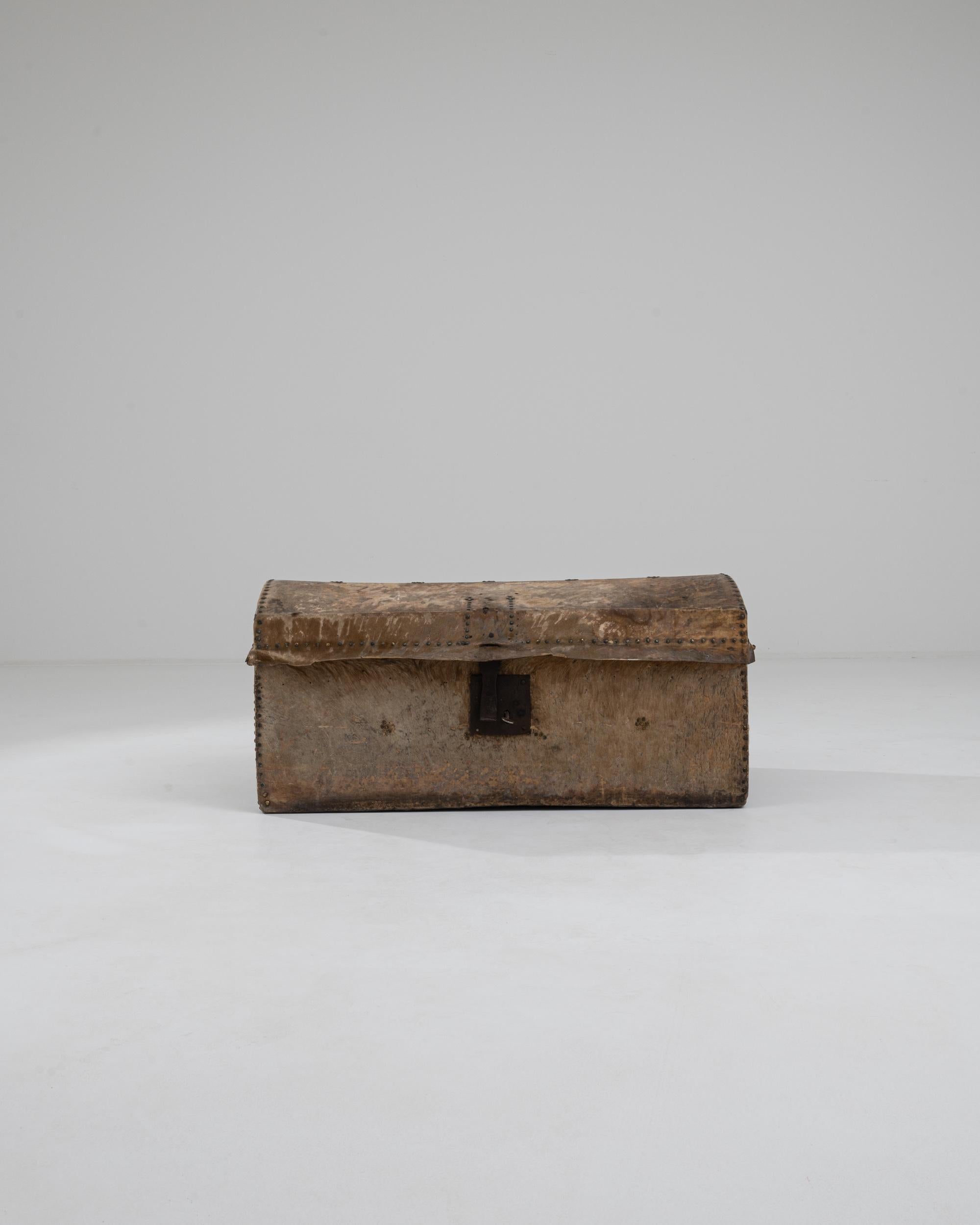 The rugged simplicity of this antique trunk has a timeless appeal. Made in France in the 1800s, the wooden case is bound in a leather cowhide. The hair of the animal is still visible in places, giving the trunk an earthy, rustic tactility, while