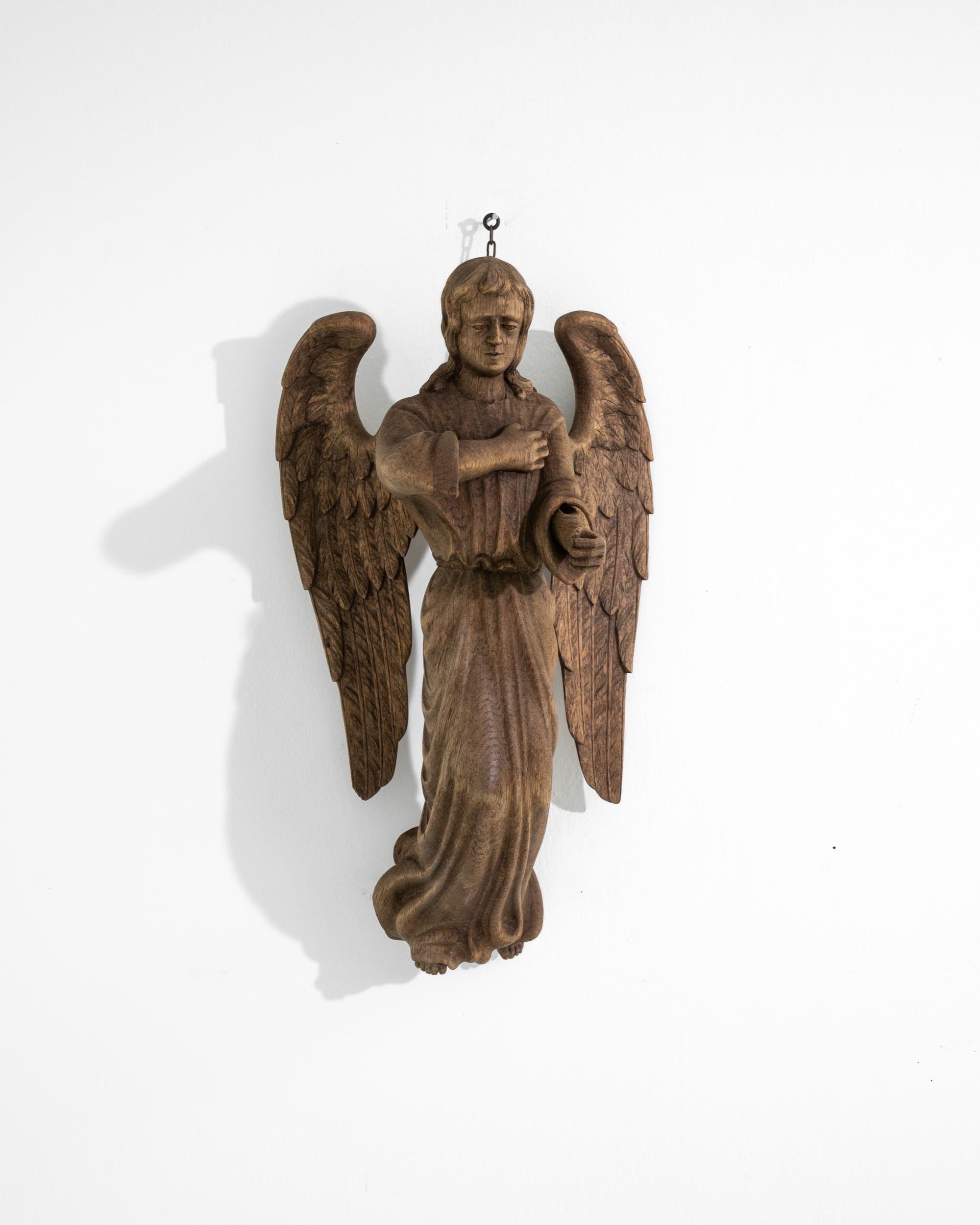 This statue of an angel was sculpted from a solid oak mass in France in the 19th century. The hand-carved craftsmanship is displayed through the faultless representation of folds, rippling on his monk's habit as if the creature was floating in the