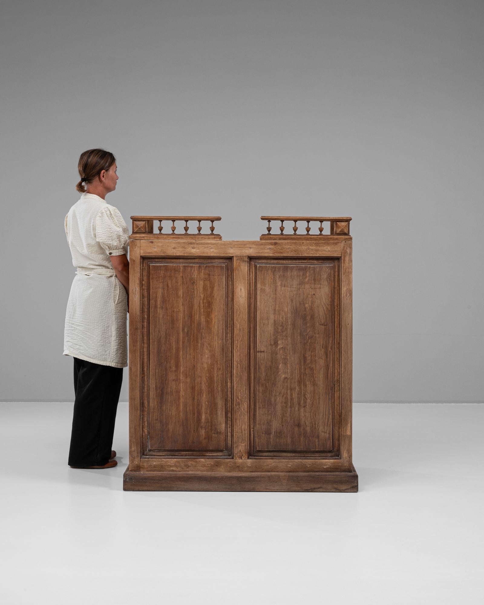 This 19th-century French wooden bar exudes rustic sophistication, blending functionality with timeless elegance. Crafted from solid wood, it features paneled sides and a sturdy rectangular base, accented by a charming balustrade detail at the top.