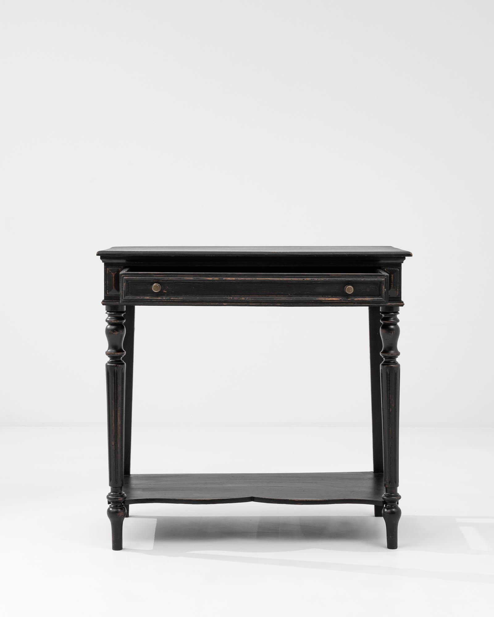 Introduce an air of timeless sophistication into your living space with this 19th Century French Wooden Black Patinated Side Table. The single drawer ensures practical storage, while the intricately designed platform near the legs doubles as a