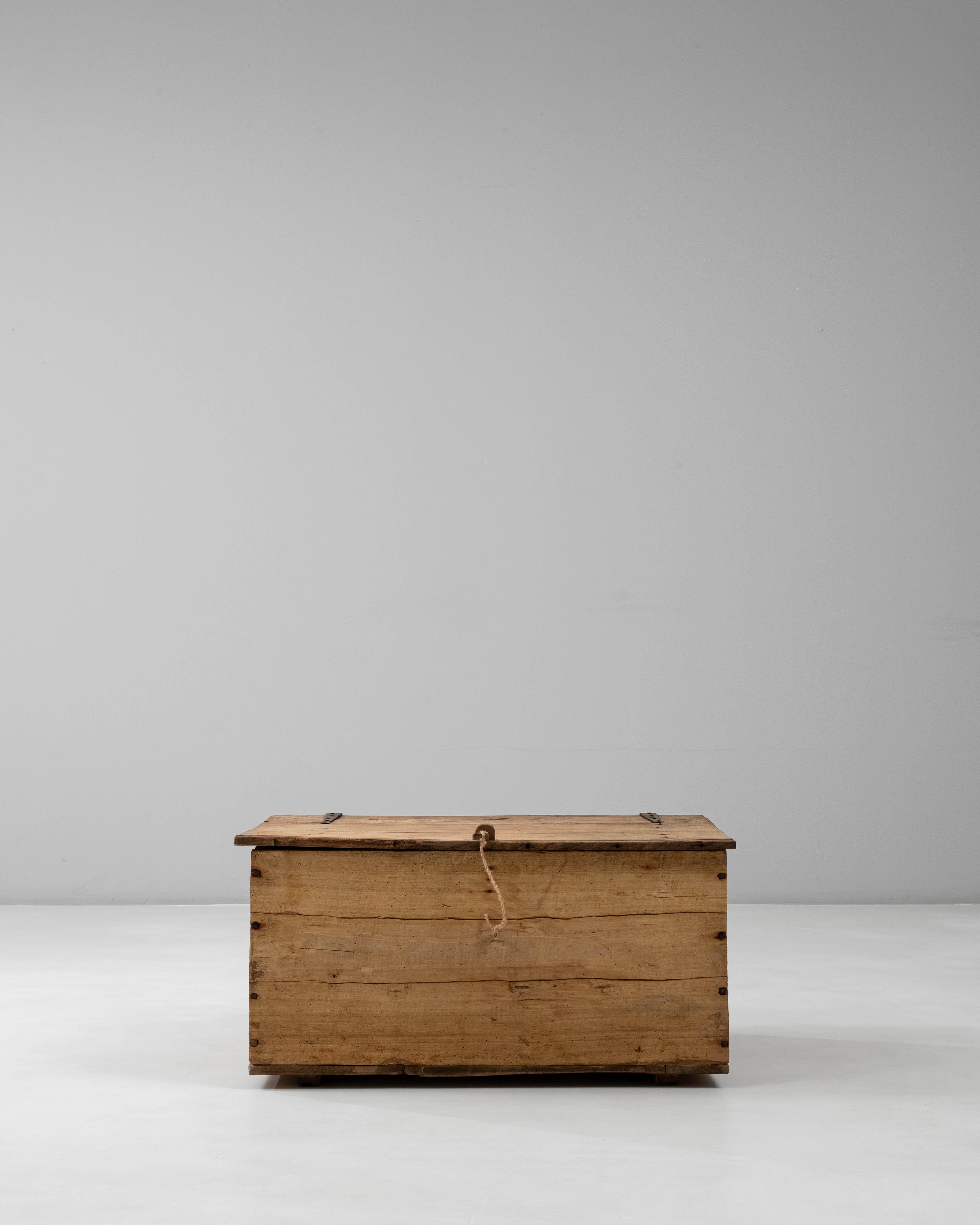 Questa cassapanca francese in legno del XIX secolo riflette la bellezza utilitaria dell'artigianato rurale. Costruito da solide assi di legno naturale, presenta un coperchio a cerniera, maniglie laterali in ferro forgiato e una falegnameria a vista