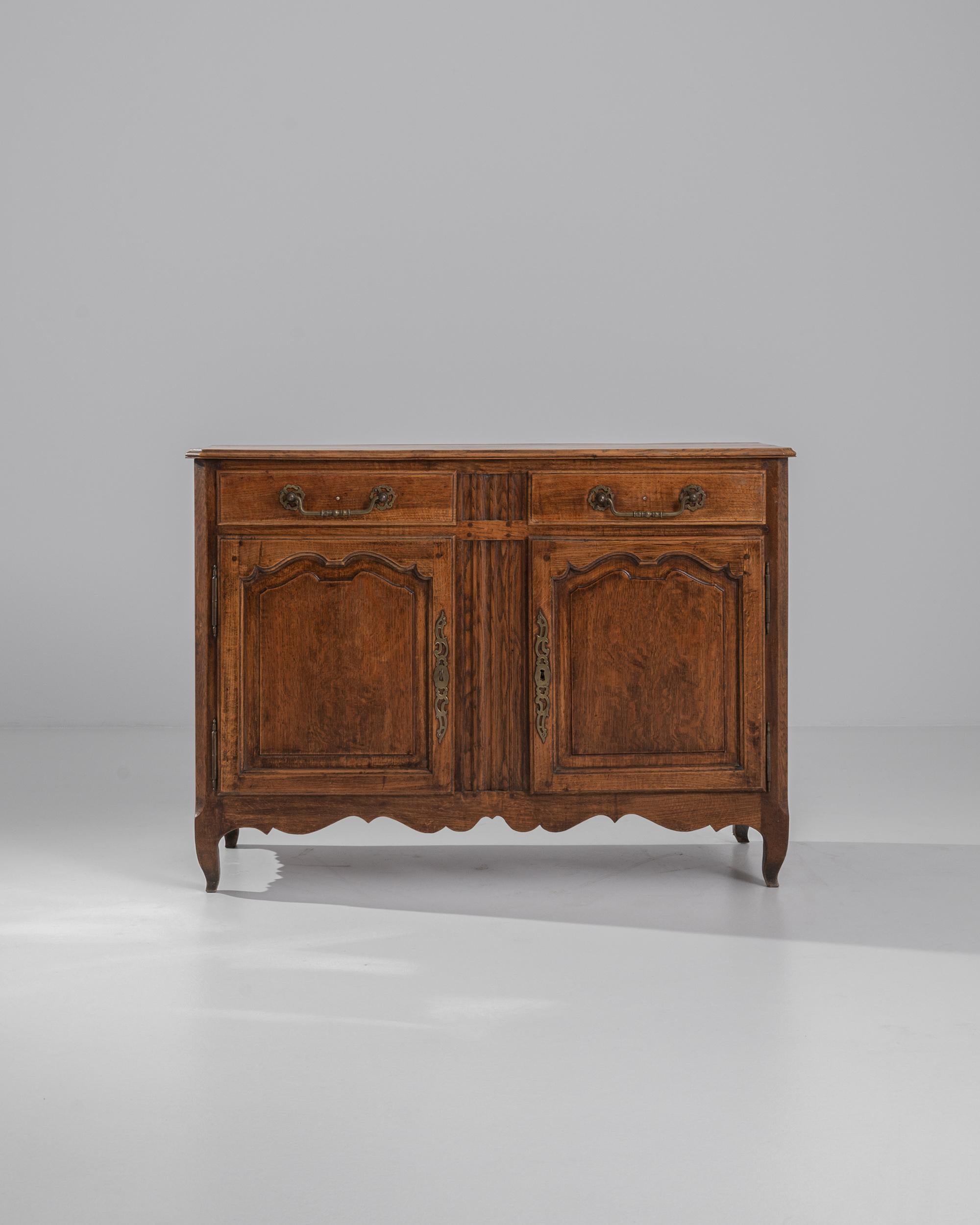 Lively decorative accents and a beautiful original patina give this antique provincial buffet a vivacious character. Made in France in the 1800s, the oak has aged to a bright, rich amber tone, inflected with a brindled grain. The scalloped curves