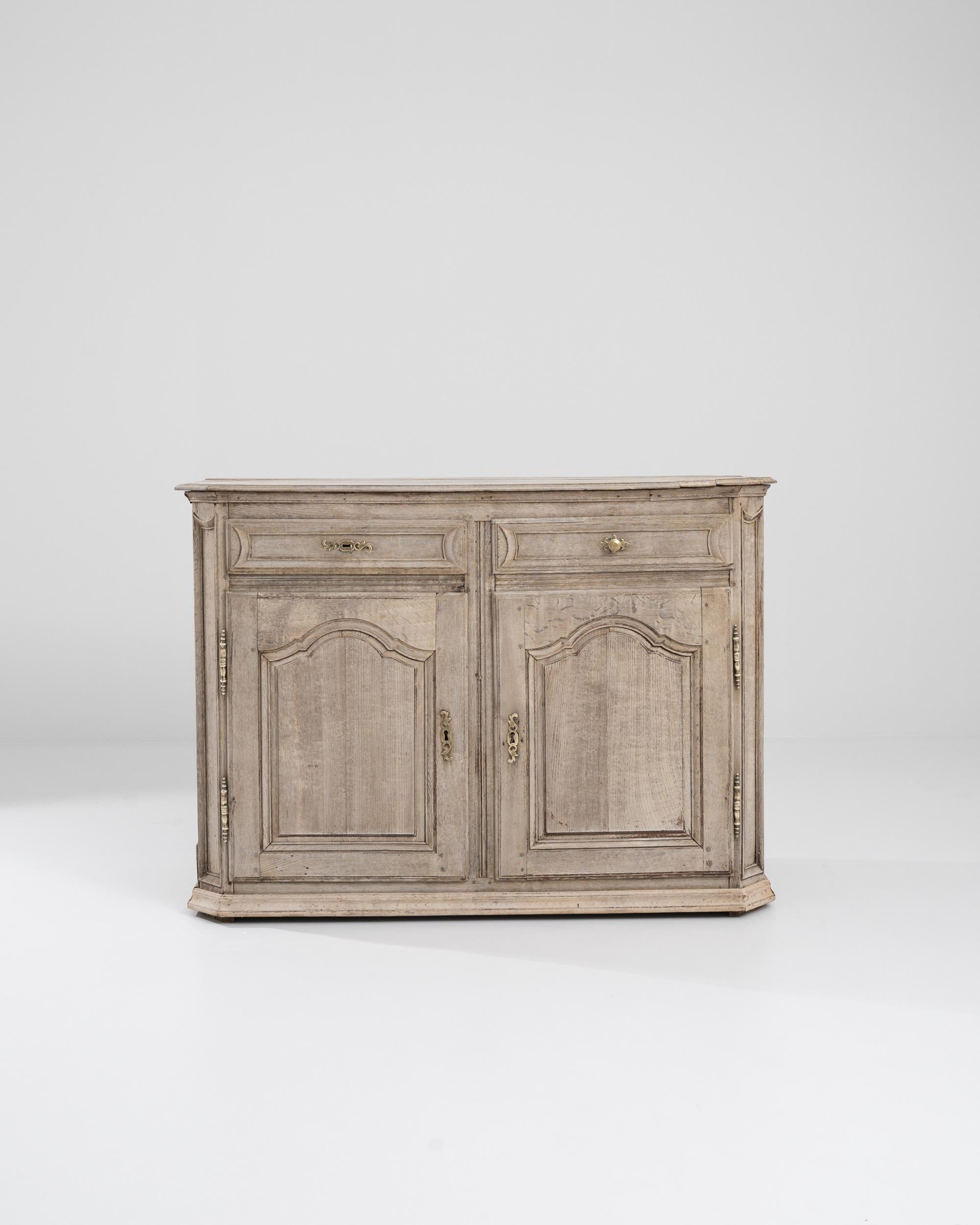 A French wooden buffet from the 19th Century. Sumptuously hand carved paneling details the two upper drawers and two large storage compartments that comprise this bleached oak buffet. A pleasing patina has spread across the surface of this buffet as