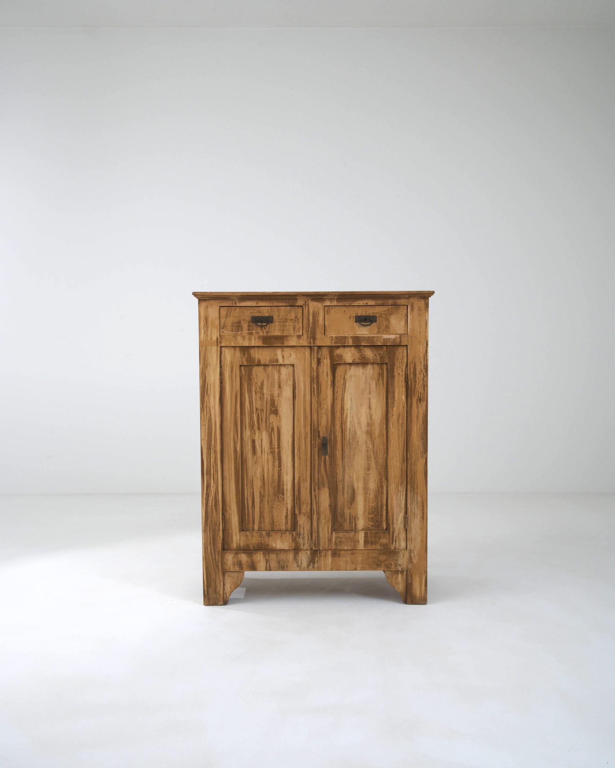 Combining clean lines with a rustic patina, this antique wooden buffet possesses a country simplicity. Built in France in the 1800s, the restrained shape of the upright cabinet makes the rough strokes of the patinated wood all the more striking.