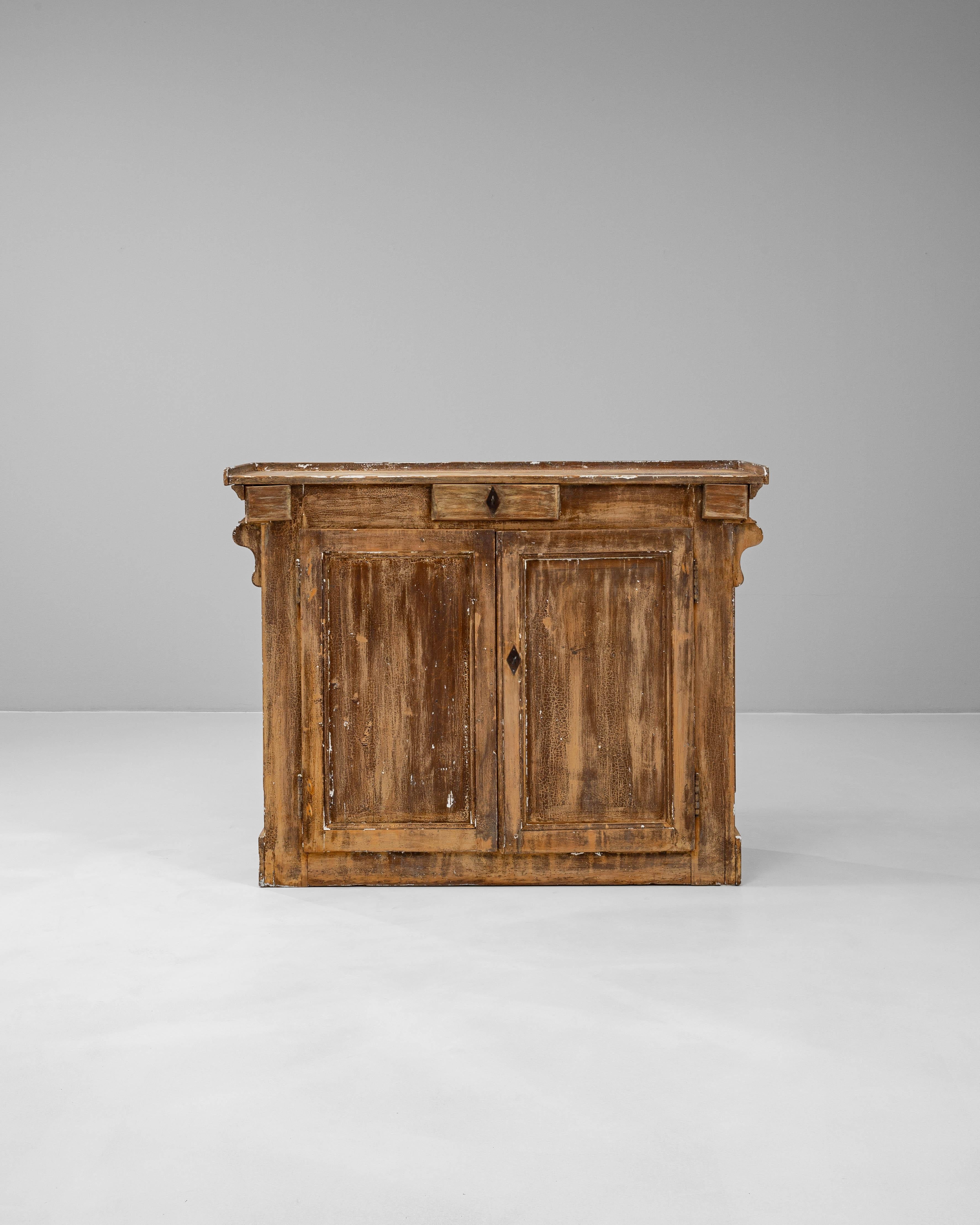This 19th Century French wooden buffet exudes rustic charm and enduring craftsmanship. Constructed from solid wood, its weathered finish and naturally aged patina reflect decades of use and character. The façade features two paneled doors and a