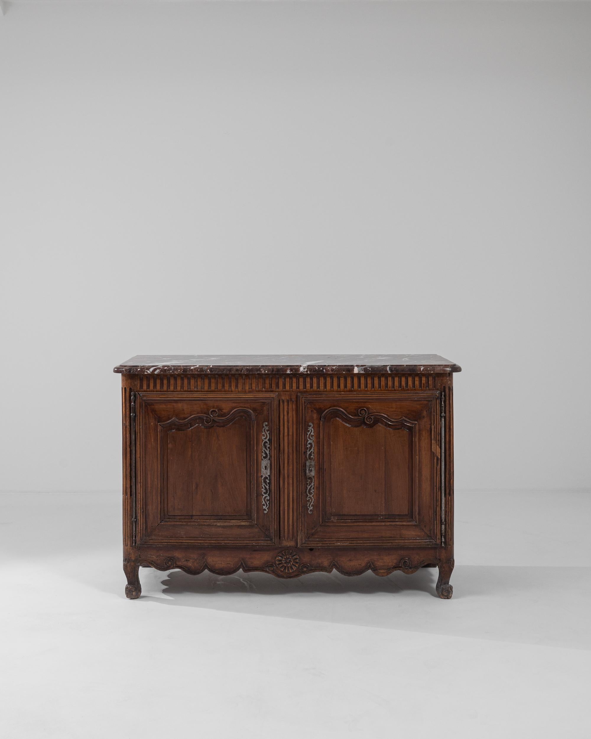 A marble tabletop gives this antique wooden buffet an opulent crowning touch. Made in France in the 1800s, the design combines a variety of stylistic motifs into a graceful, harmonious whole. Fluted accents and carved rosettes add a Neoclassical