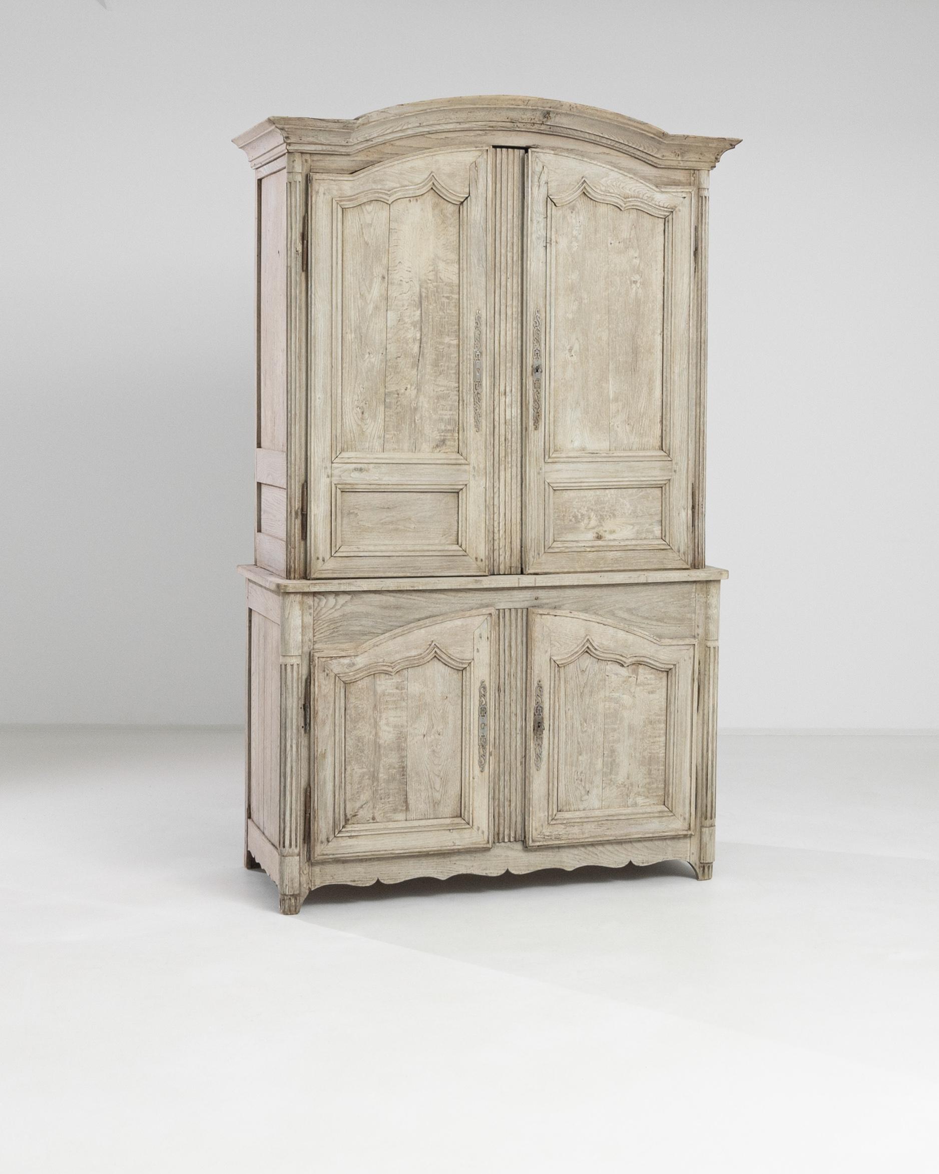 A 19th century wooden cabinet produced in France. Standing on fluted bracket feet, this large two-case cabinet displays a molded top, a scalloped apron and turned fluted edges. The exterior has been restored to a pale tone, highlighting the organic