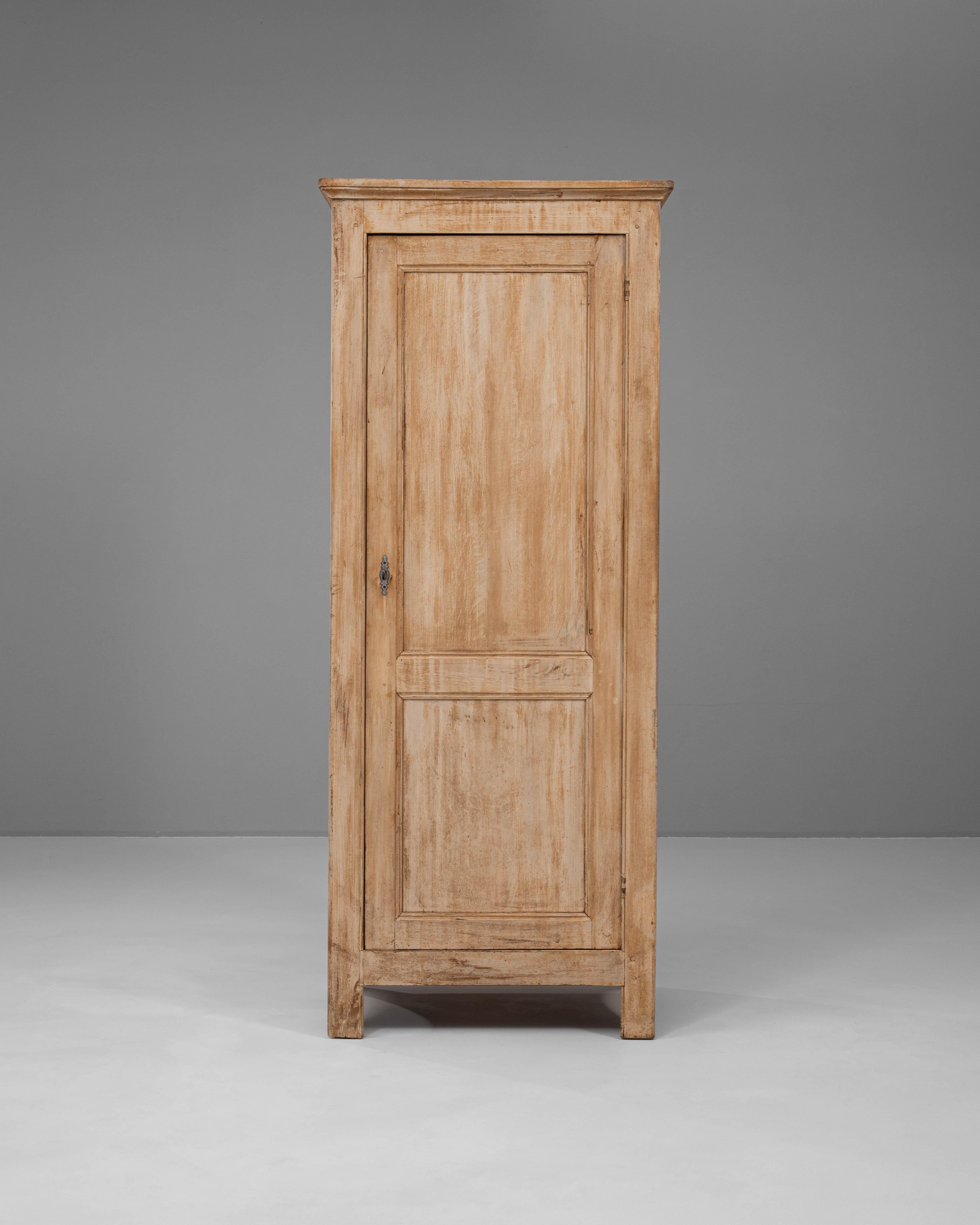 This 19th-century French wooden cabinet is a refined example of rustic elegance and craftsmanship. Made from solid wood with a naturally aged patina, it features a tall, narrow structure that maximizes storage without overwhelming a space. The