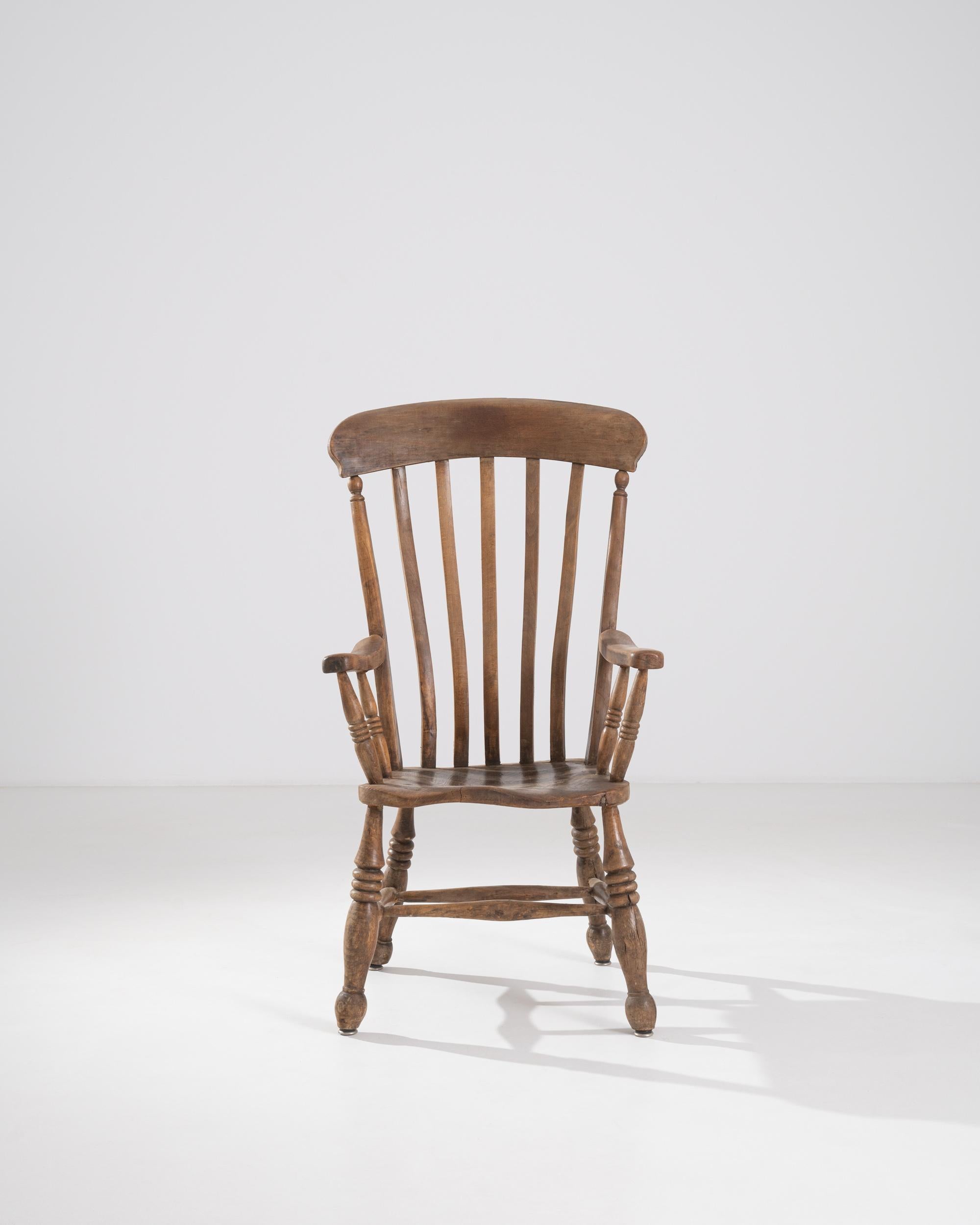 A French chair from the 19th century. This high-backed chair offers a comfortable and elevated moment of rest. Tapering and waving spindles above sloping arm rails and lathed legs create a harmonious synergy throughout its construction. Its rich and