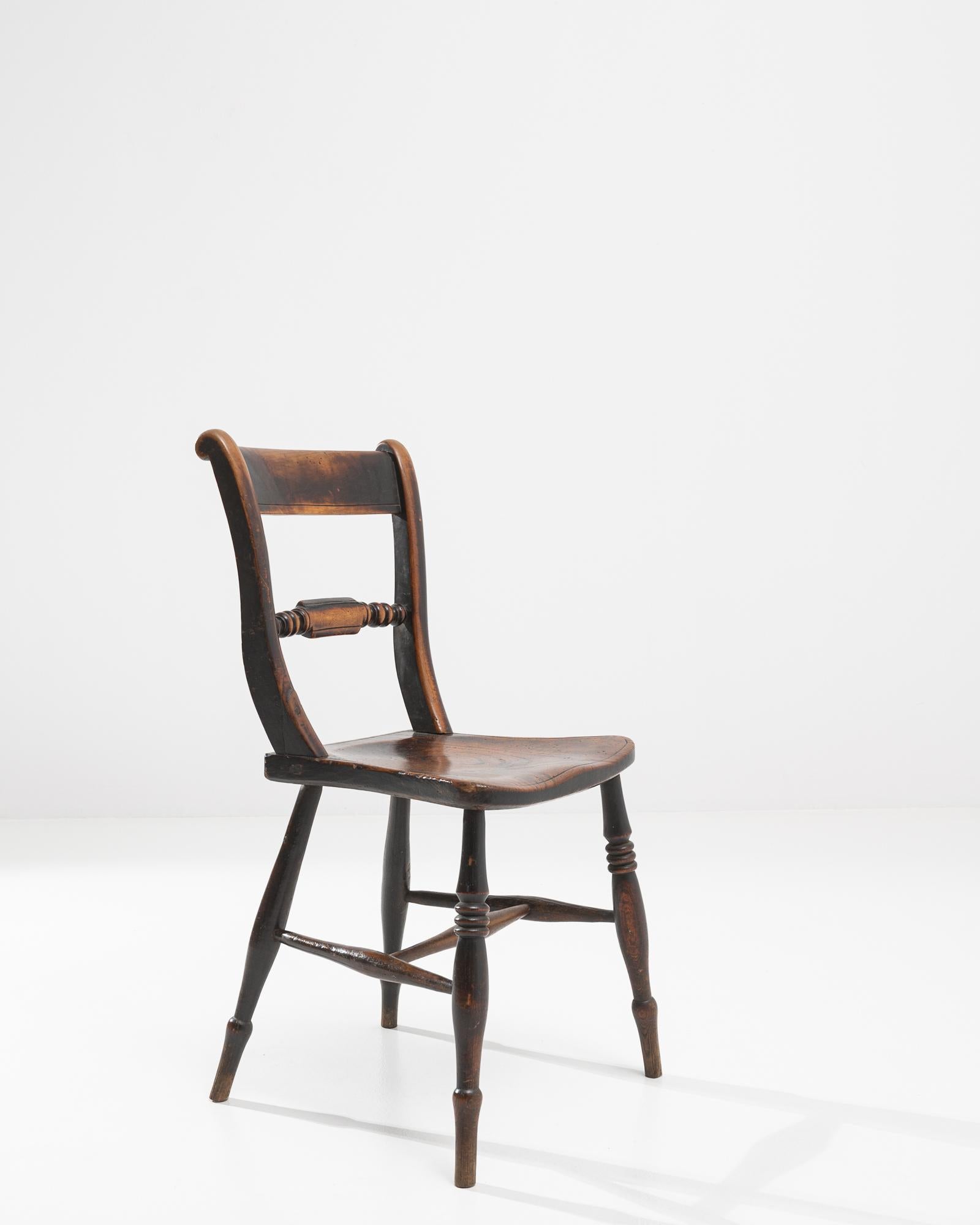 This 19th Century French Wooden Chair epitomizes rustic charm and the enduring elegance of French country design. Each curve and spindle speaks of the chair's handcrafted origins, with a lovingly worn patina that only time could bestow. The warmth