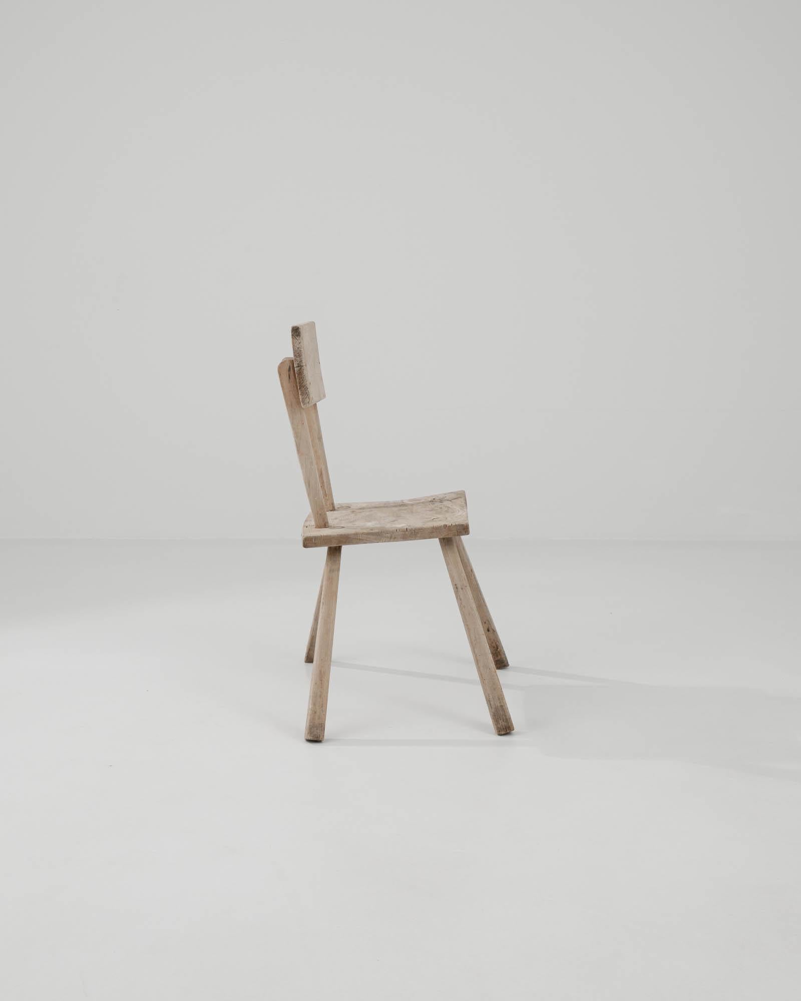 Embrace the rustic allure of this 19th Century French Wooden Chair, a piece that speaks volumes of its storied past. Its minimalist design, with a straight backrest and a solid seat, reflects the honest carpentry of a time when simplicity was