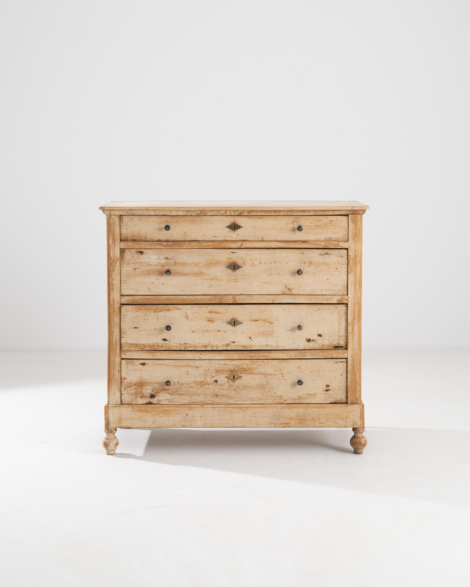 A wooden chest of drawers from 19th century France. A bright and time-etched patina, as well as exposed wood knots and grain details enliven this chest with a rustic cheer. However, carefully lathed feet, smartly fit diamond keyholes, and an