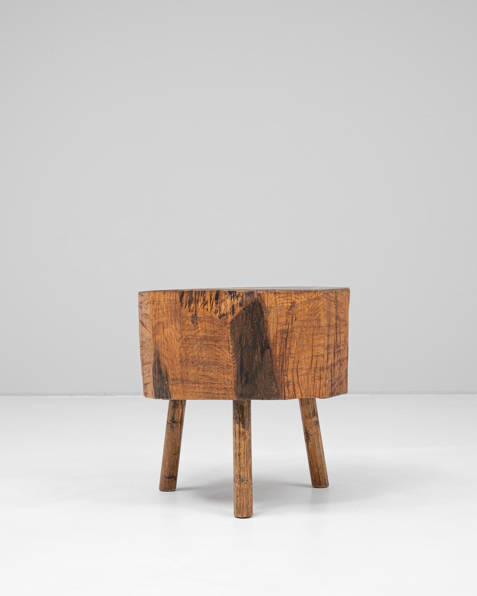 This 19th Century French wooden coffee table showcases the enduring strength and rustic elegance of traditional craftsmanship. Carved from a single thick block of wood, the top retains visible tool marks and a beautifully weathered surface that