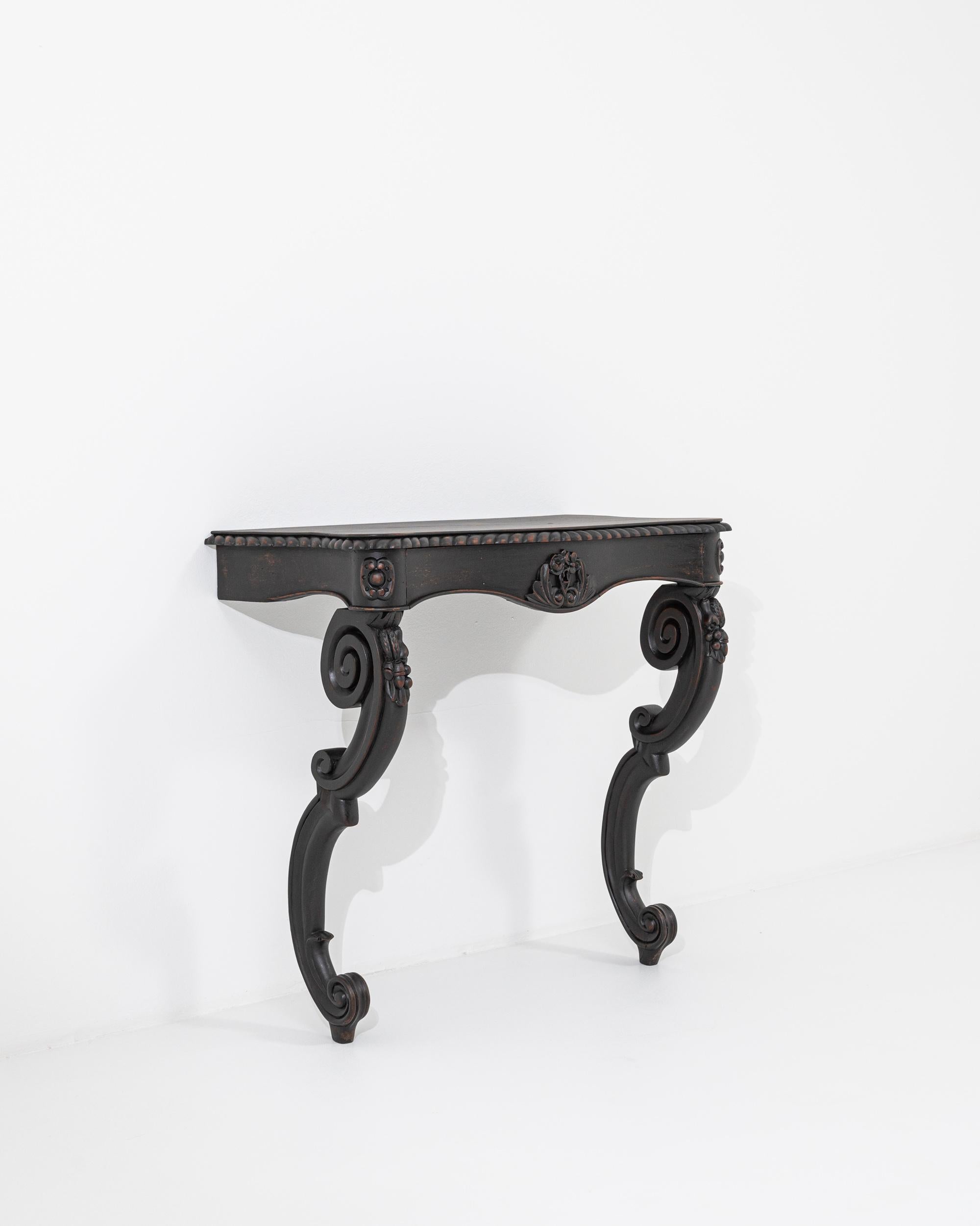 A wooden console table created in 19th century France. This console table has a unique gravity, constructed to appear as though it is emerging right out of the wall, with its spiraling, carved legs coming up and over to rest gracefully upon the