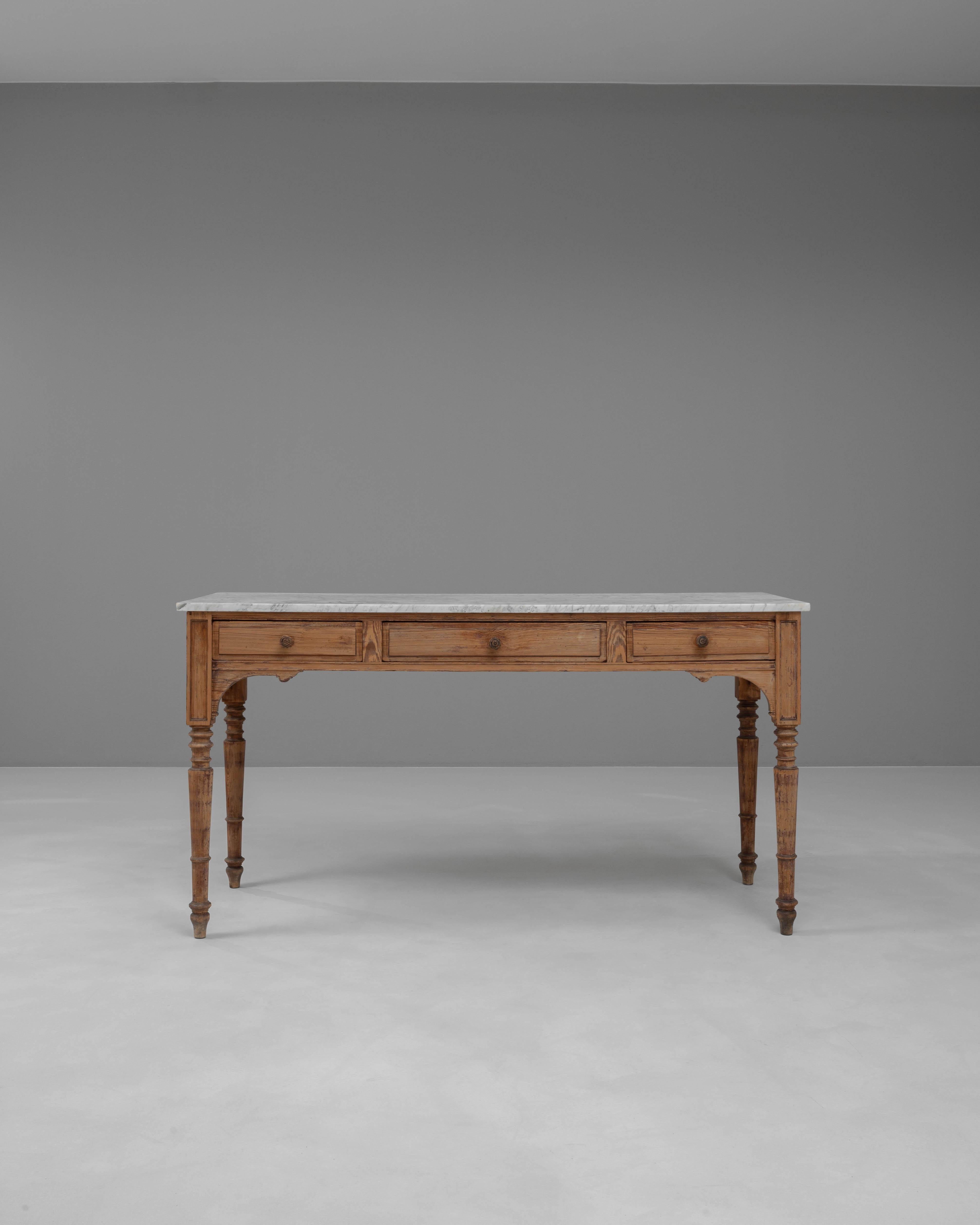 This 19th-century French wooden console table exudes classic elegance with its beautifully crafted design and practical features. The sturdy, carved wooden frame is complemented by a pristine marble top, providing a durable and luxurious surface