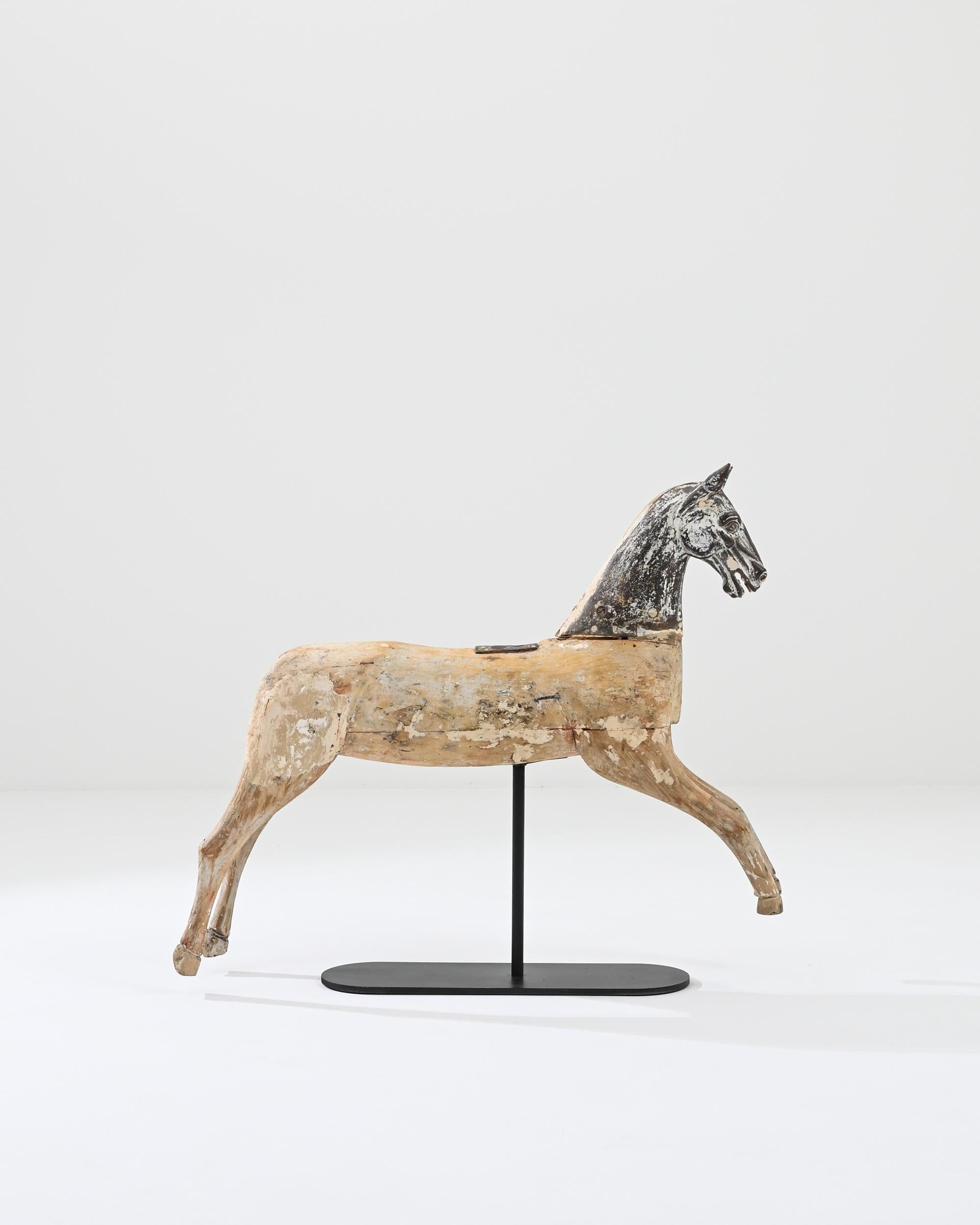 A wooden sculpture of a horse made in 19th century France. A horse mid-gallop has been frozen in time by the immaculate sculpting of 19th century artisans. Its springing legs and upbeat expression exude an energy of play, while the dramatic patina