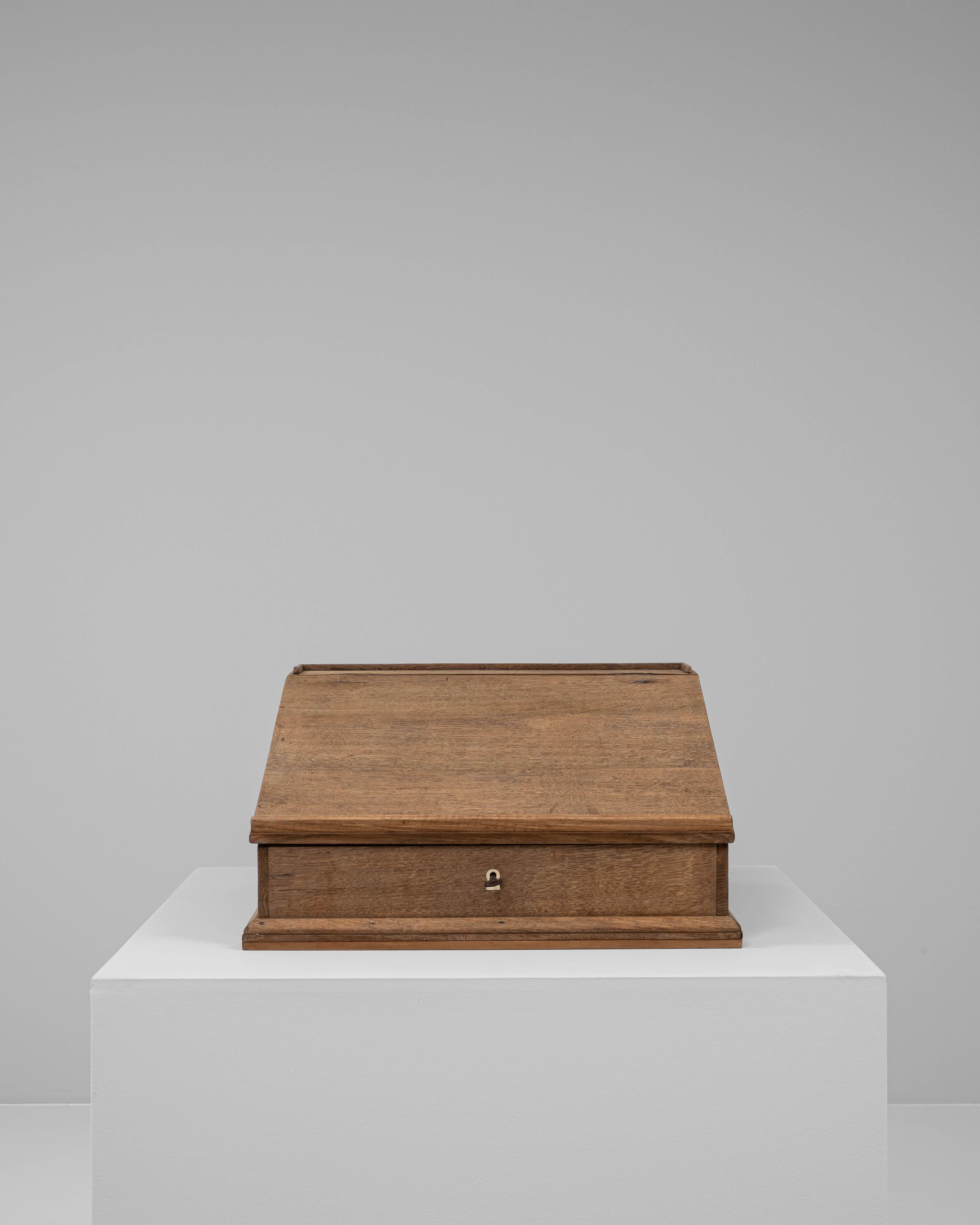 This 19th century French wooden desk organizer exemplifies functional craftsmanship with its simple, utilitarian design. Made from solid wood, it features a slanted lid that opens to reveal divided storage compartments, once used for keeping