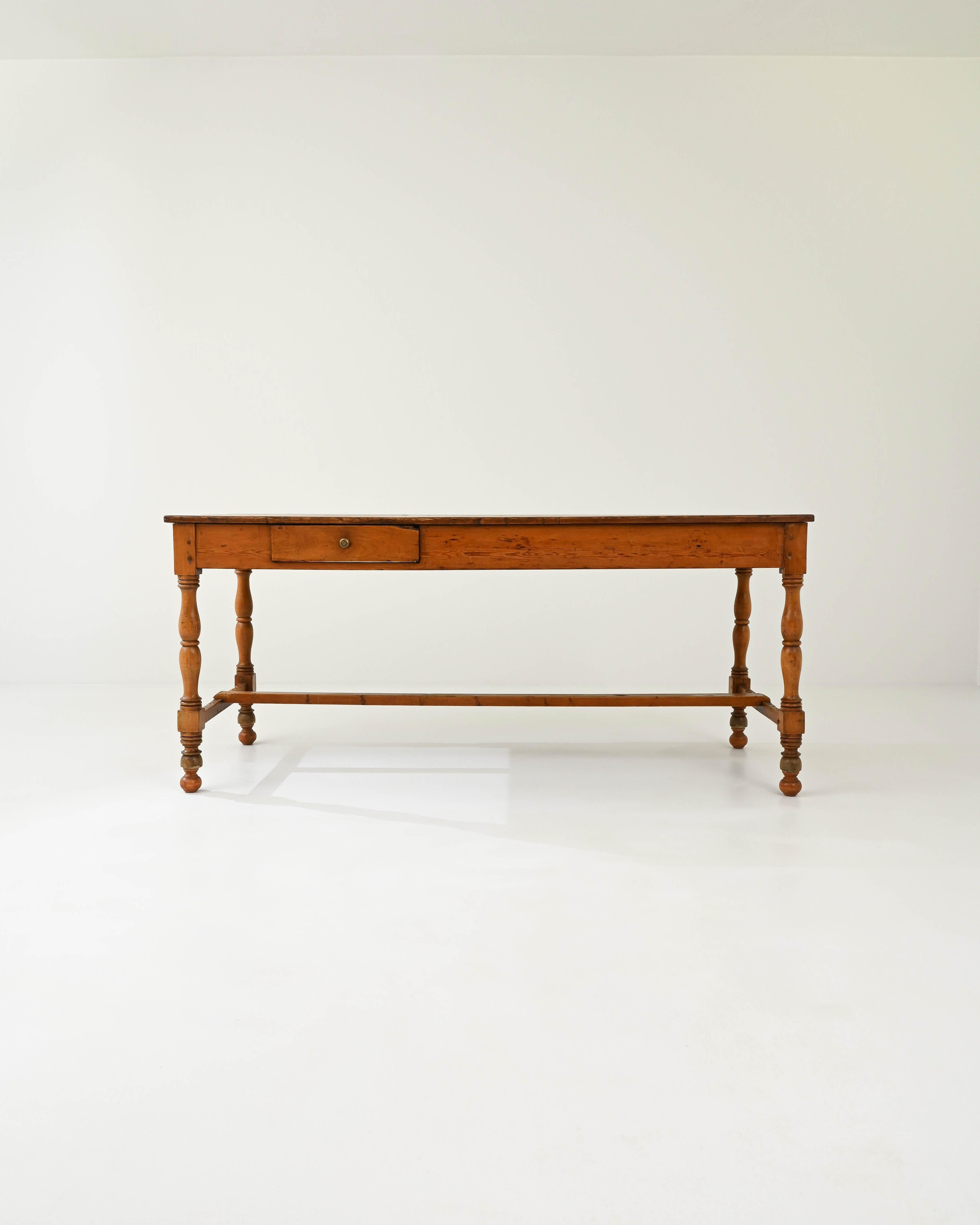 A wooden dining table created in 19th century France. Bright and cheery, yet crafted with a sense of dignity, this long and slender table communicates a sense of grace and joy. With mortise and tenon joints, a classic trestle construction, and