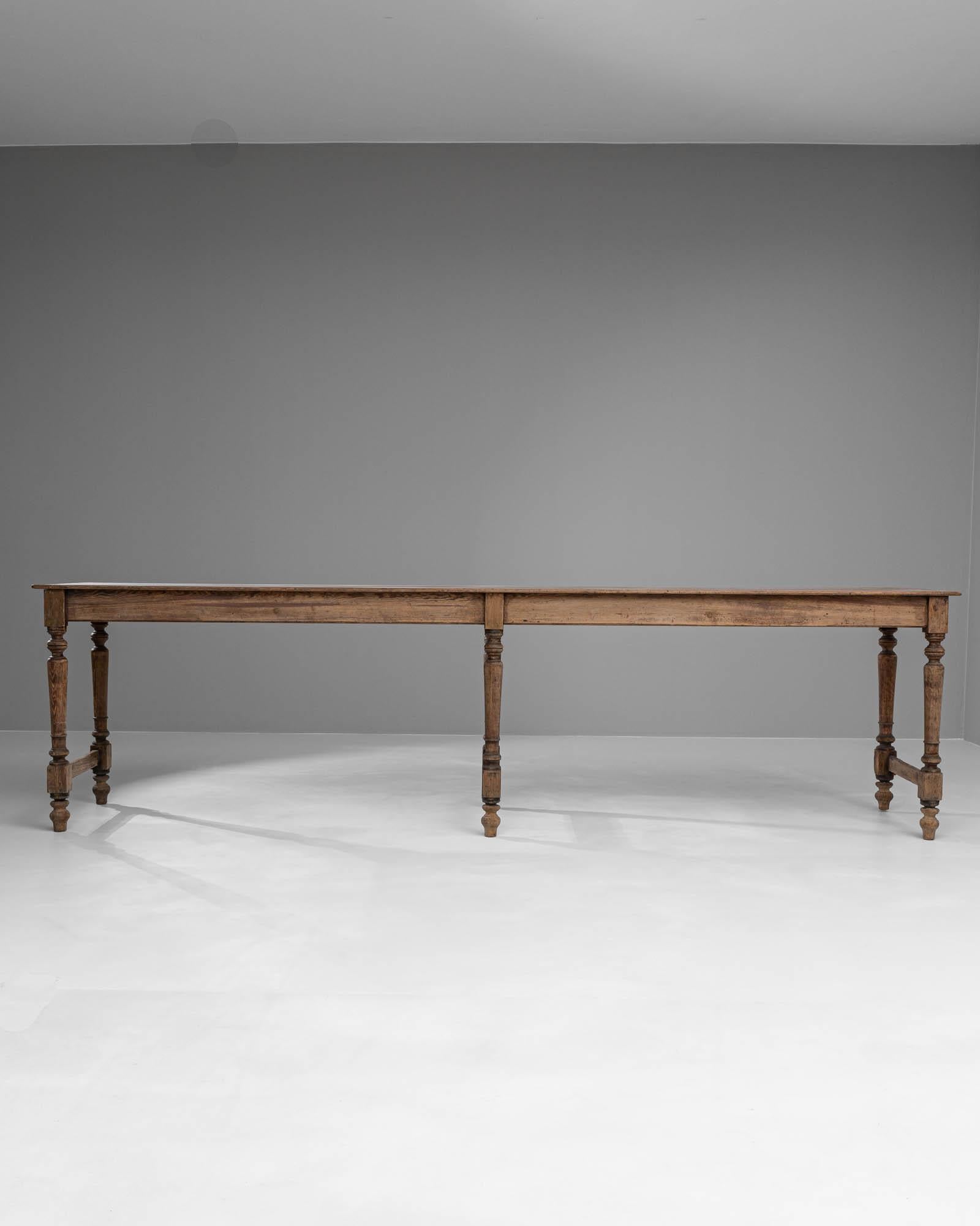 Dieser französische Holztisch aus dem 19. Jahrhundert strahlt die rustikale Eleganz vergangener Zeiten aus und versprüht historischen Charme. Der aus Massivholz gefertigte Tisch wird von fein gedrechselten Beinen getragen, die durch eine robuste,