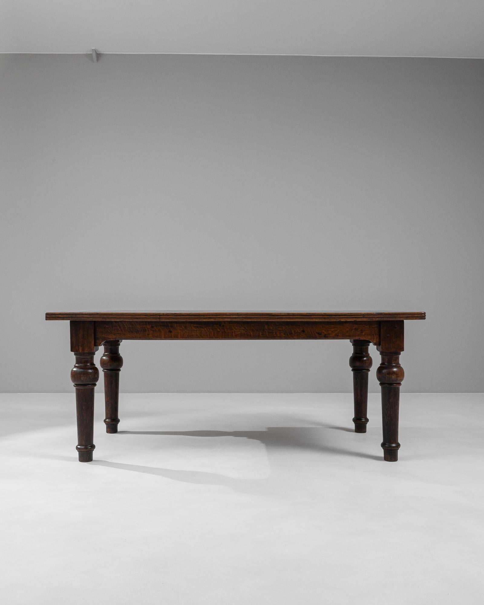 This exquisite 19th-century French wooden dining table radiates the grandeur and charm of its era. Constructed from rich, dark wood, the table features a robust, rectangular top that rests on sturdy, elegantly turned legs. Each leg is connected by