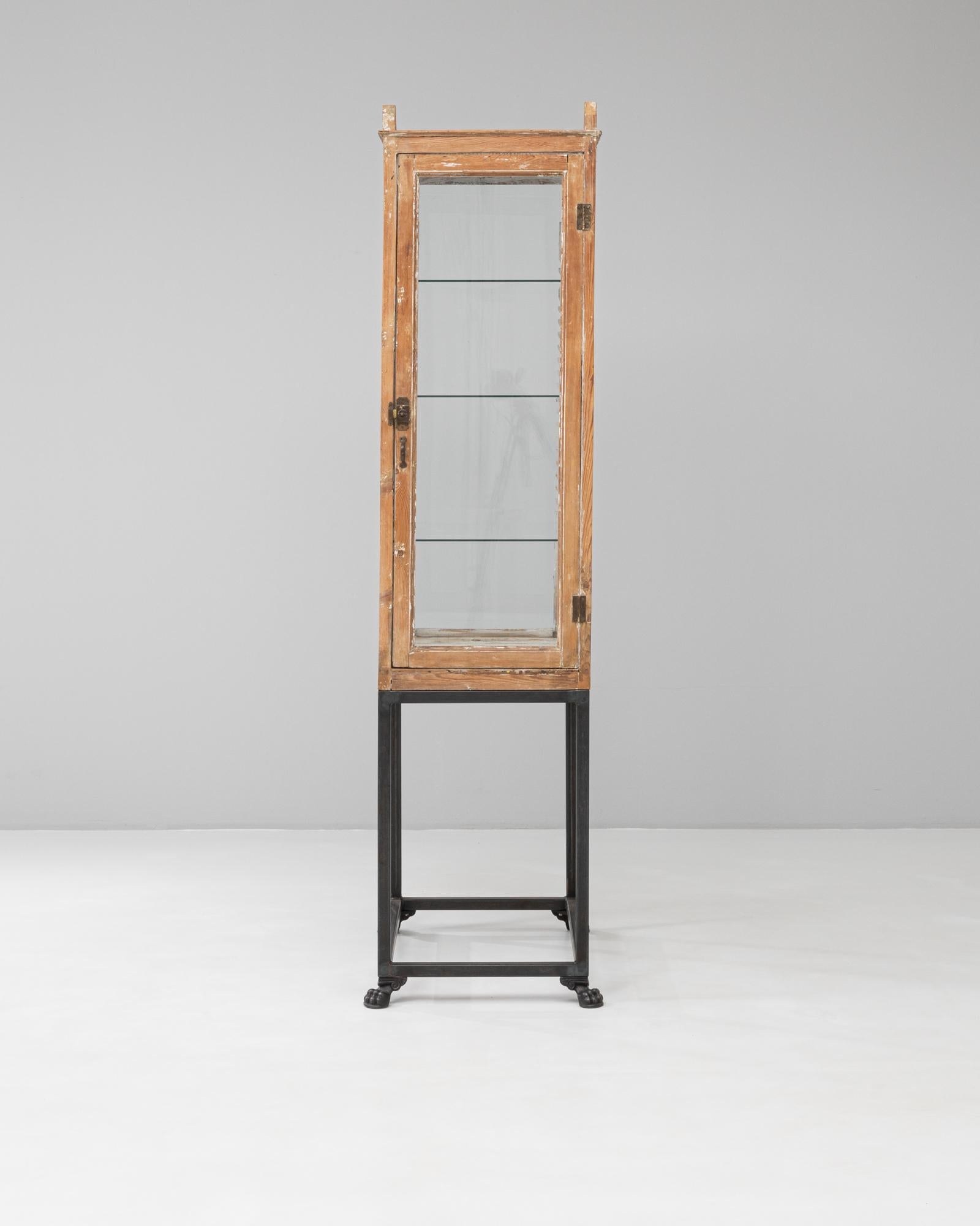 Questa vetrina in legno francese del XIX secolo combina un'artigianalità raffinata con un carattere industriale. La struttura con pannelli in vetro, realizzata in legno invecchiato naturalmente, conserva la patina originale e i terminali decorativi