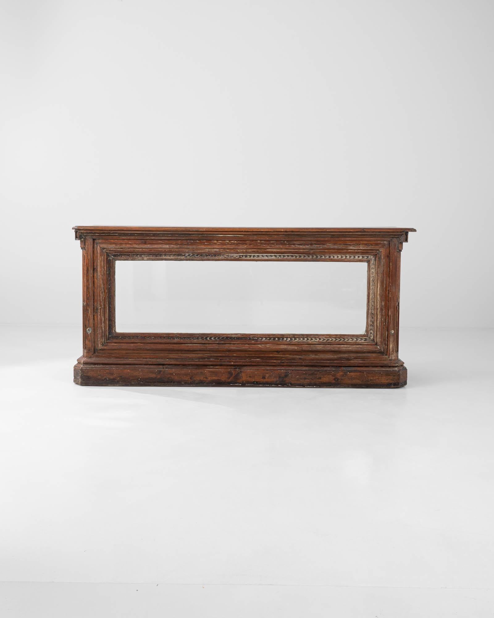 This exquisite antique counter was handcrafted in 19th-century France. It features transparent glass panels with a refined wooden case, offering a perfect view into the bar's interior. The sturdy plinth base, with beveled corners, combined with