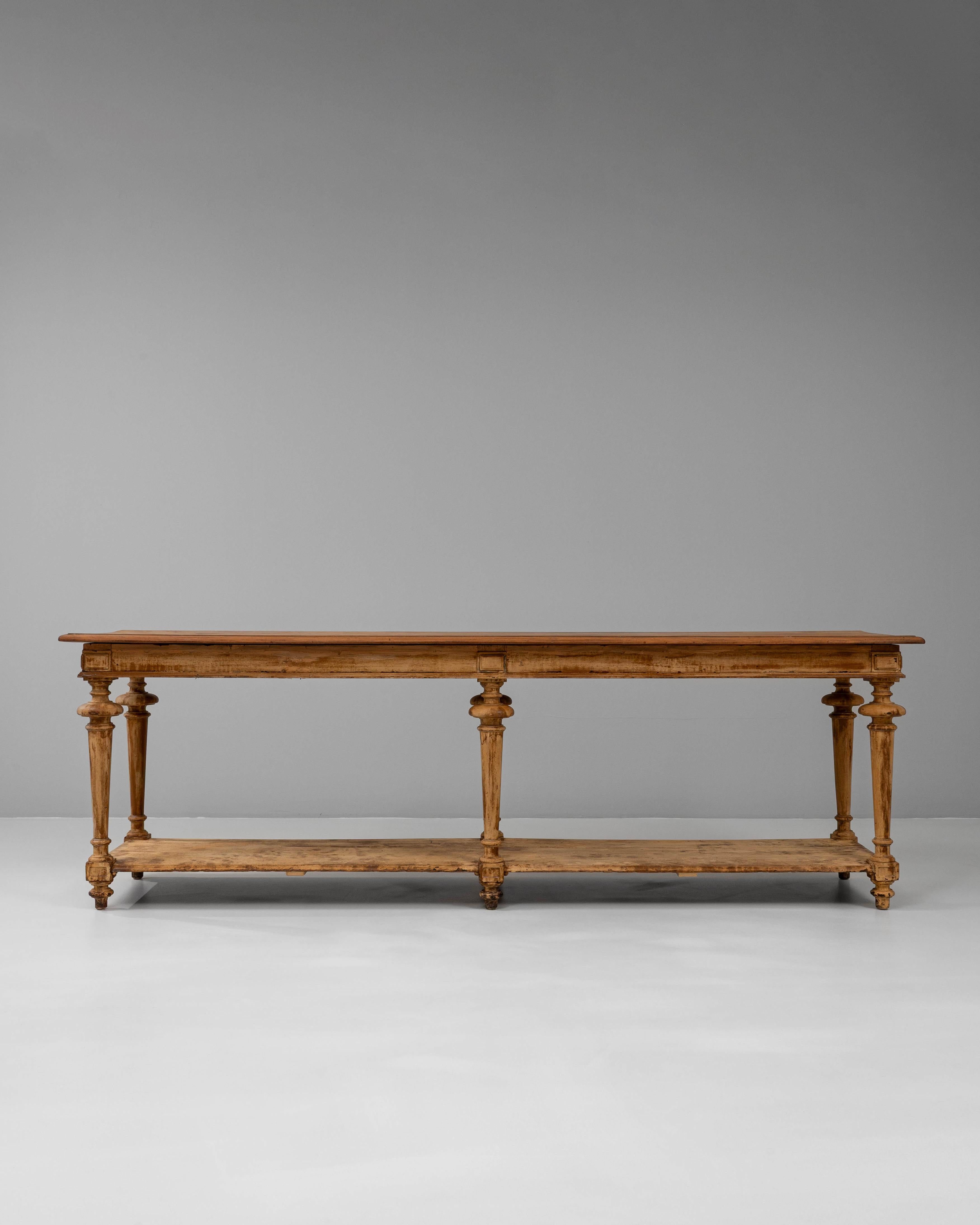 Esta mesa de pañero de madera francesa del siglo XIX presenta una forma alargada y elegante, de proporciones clásicas, con patas bellamente torneadas unidas por un estante inferior. La cálida pátina y el acabado desgastado por el tiempo revelan su