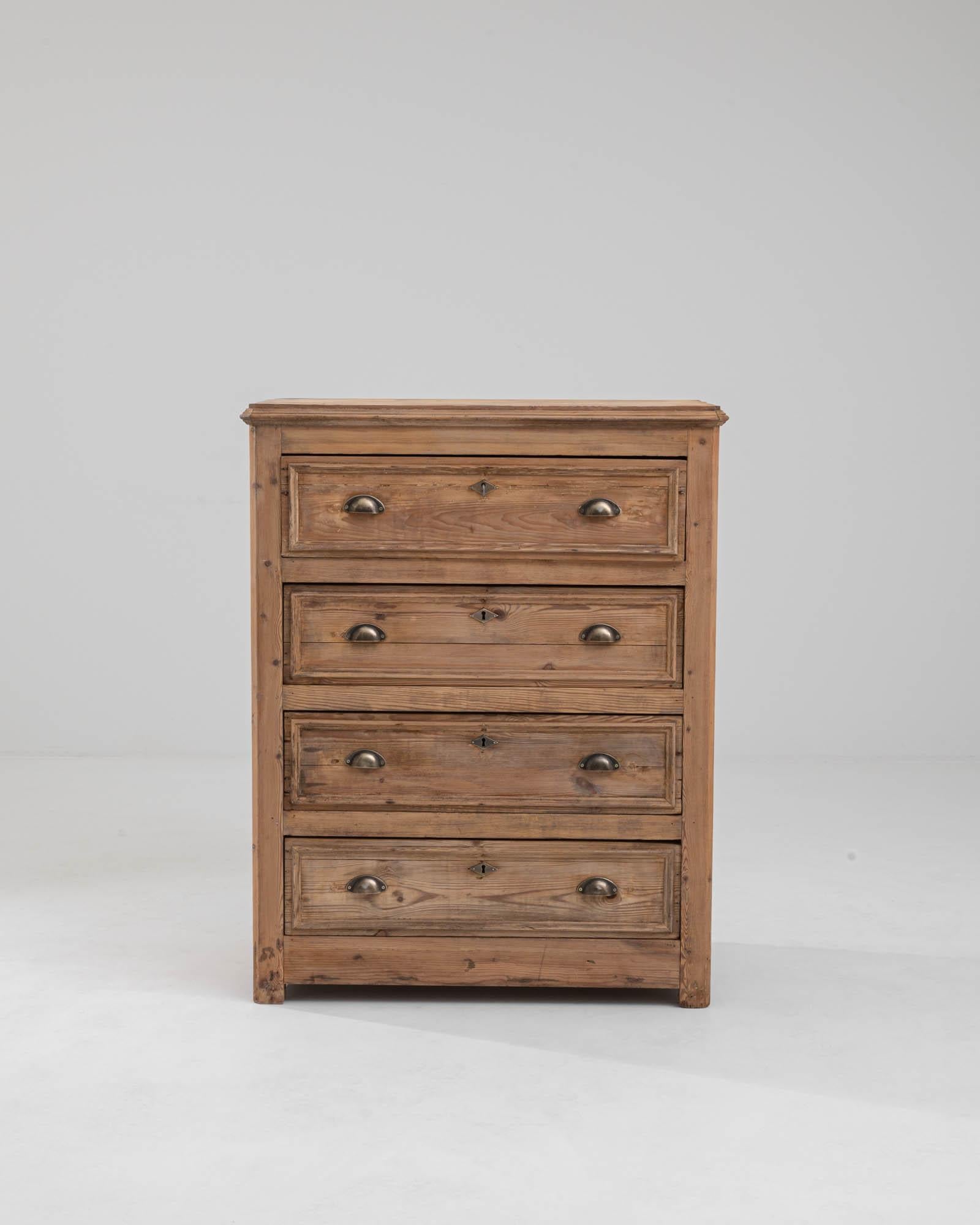 A wooden chest of drawers made in 19th century France. This chest contains four equally spacious drawers bearing brass cupped pulls and diamond-shaped keyholes. The condition of the wood has been remarkably preserved through the years, just a light