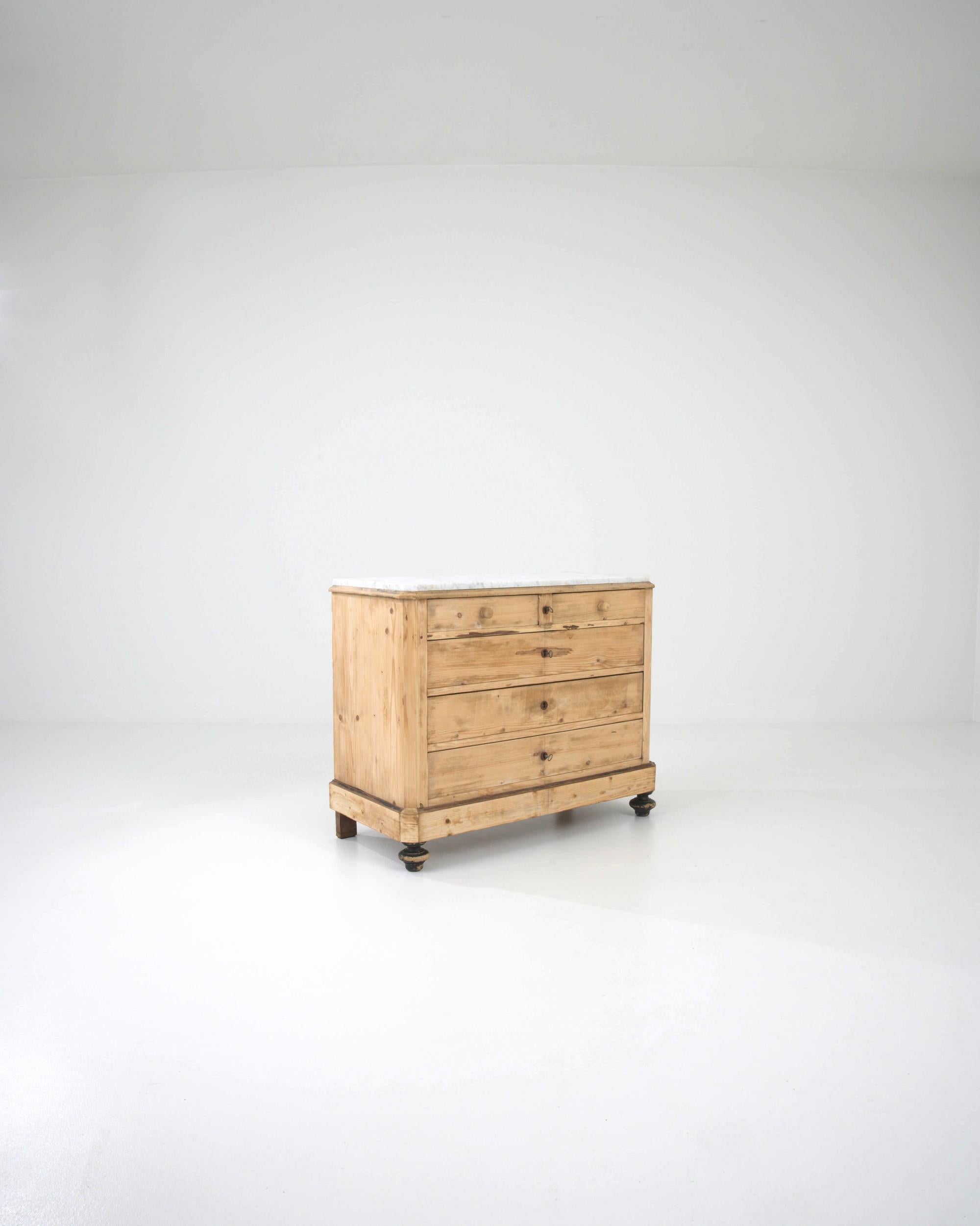 Combining a simple cabinet with a marble tabletop, this antique chest of drawers strikes an attractive balance between the homey and the luxurious. Made in France in the 1800s, the design of the case is clean and unornamented. Faceted corners lend