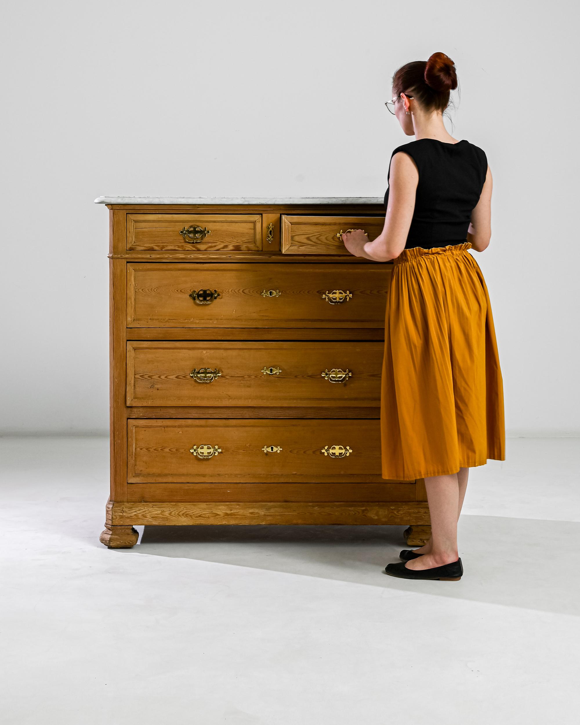 This 19th century chifonier made in France boasts a refined marble top, resting over a wooden case with three deep and two shallow drawers adorned by gilded bail pulls. A curious angularity of its sturdy feet accentuate a noble neoclassical profile