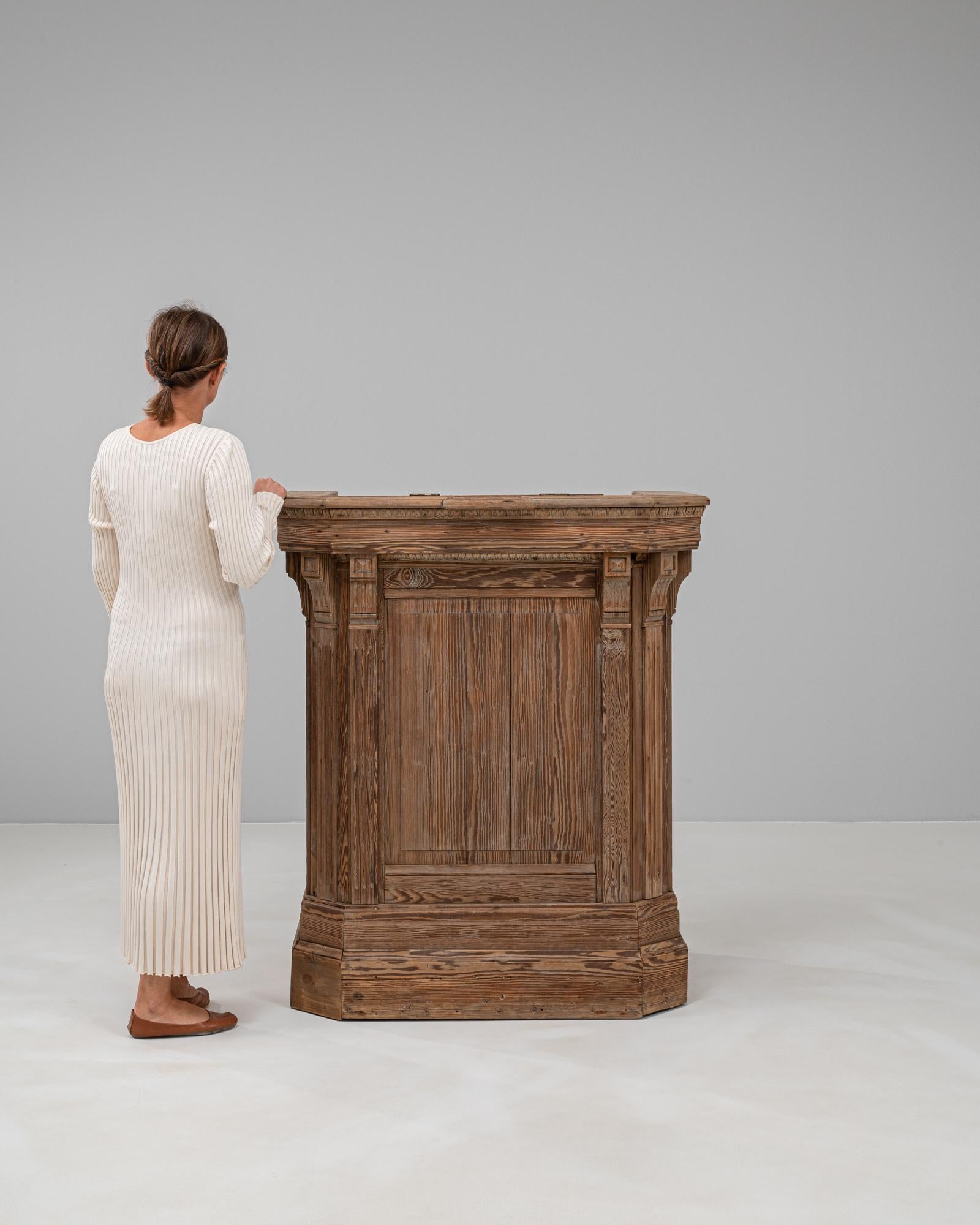 Crafted in the 19th century, this French wooden lectern exudes timeless charm with its rich patina and intricate detailing. Made from solid wood, it features elegant hand-carved embellishments along the edges, adding a touch of refinement. The front