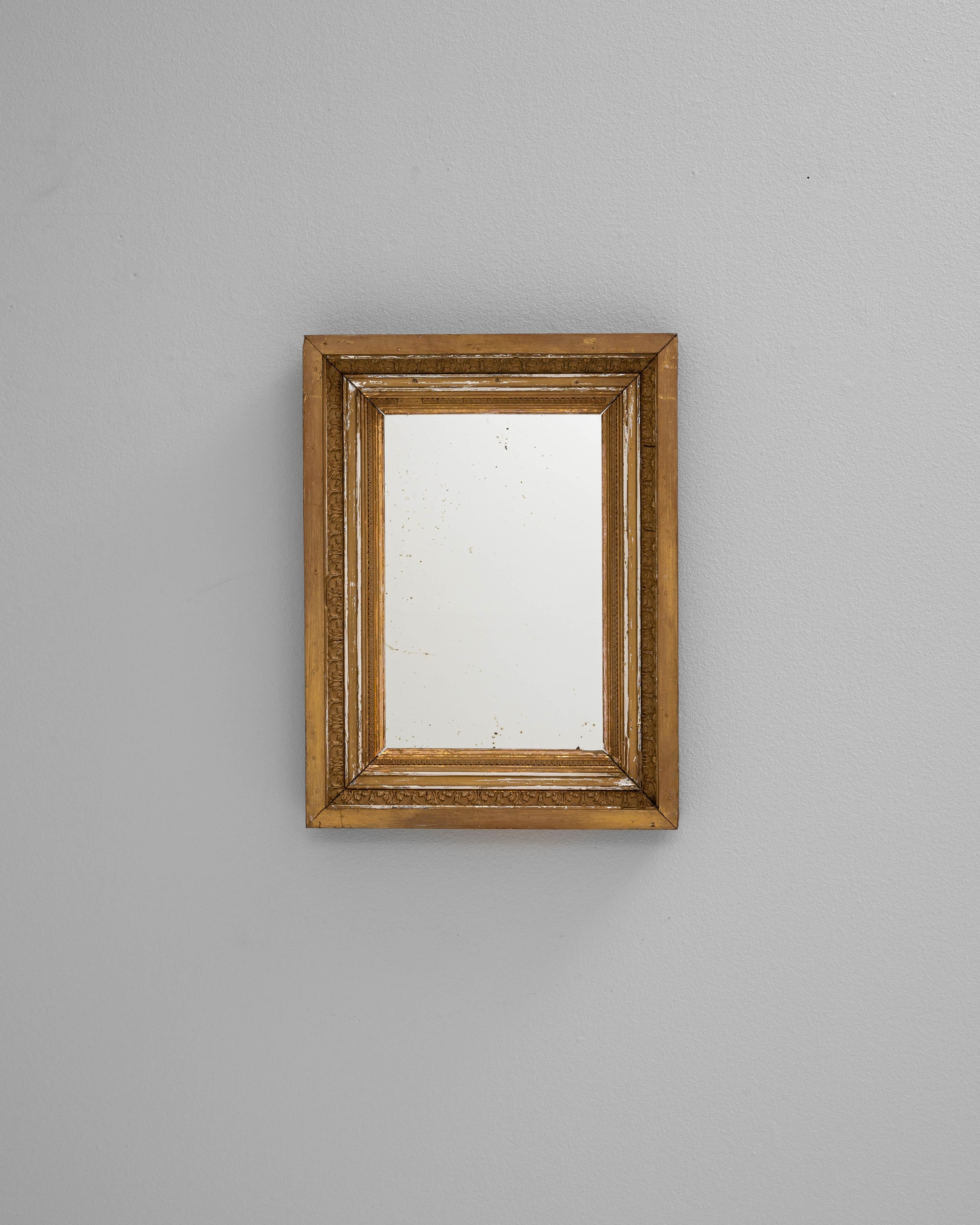 Ce miroir en bois français du XIXe siècle dégage une élégance intemporelle avec son cadre doré et ses proportions classiques. Fabriqué en bois et fini avec une patine dorée chaleureuse, le miroir présente un design de moulures en gradins qui