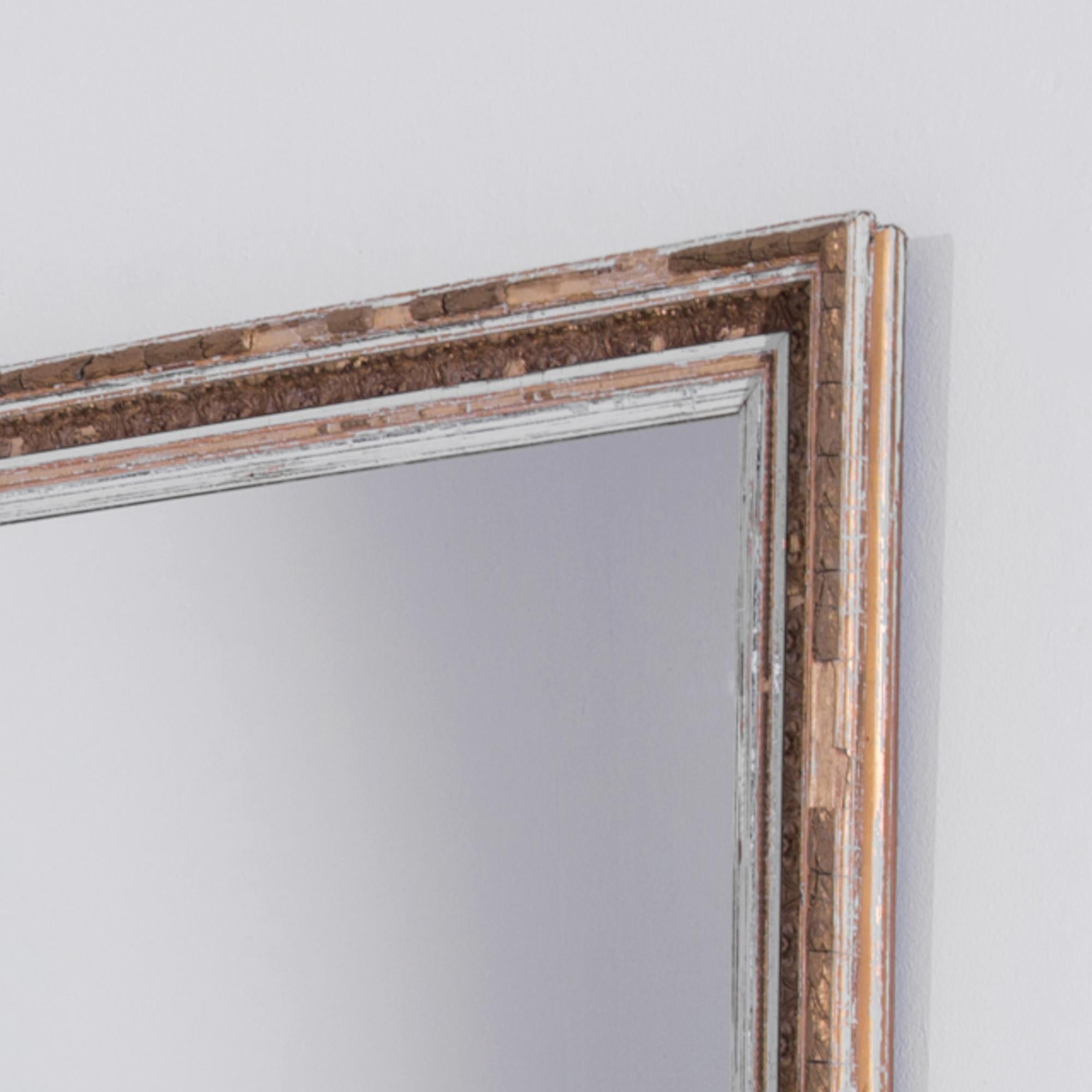 A wooden mirror crafted in France circa 1880. The white patinated frame is enlivened with an exquisite ornamentation. Three by three and a half feet, this antique looking glass resembles a window to the epoch of the 19th century bourgeois refinement.