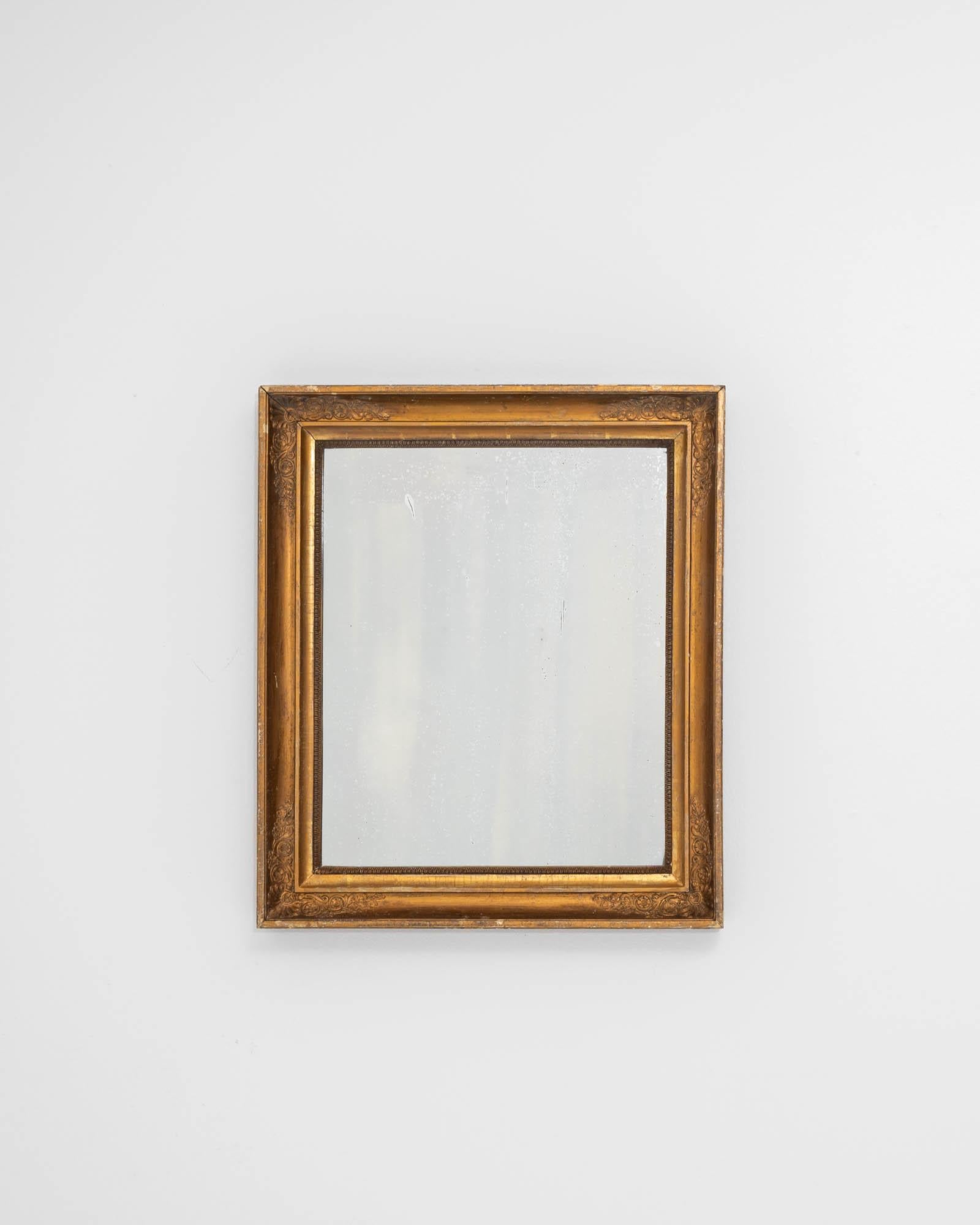 A wooden mirror created in 19th century France. Dazzlingly bright and full of a charming age and experience, this elegant mirror shimmers with class and beauty. From each of the frame’s corners, scrolled floral motifs bloom with surprising grace and