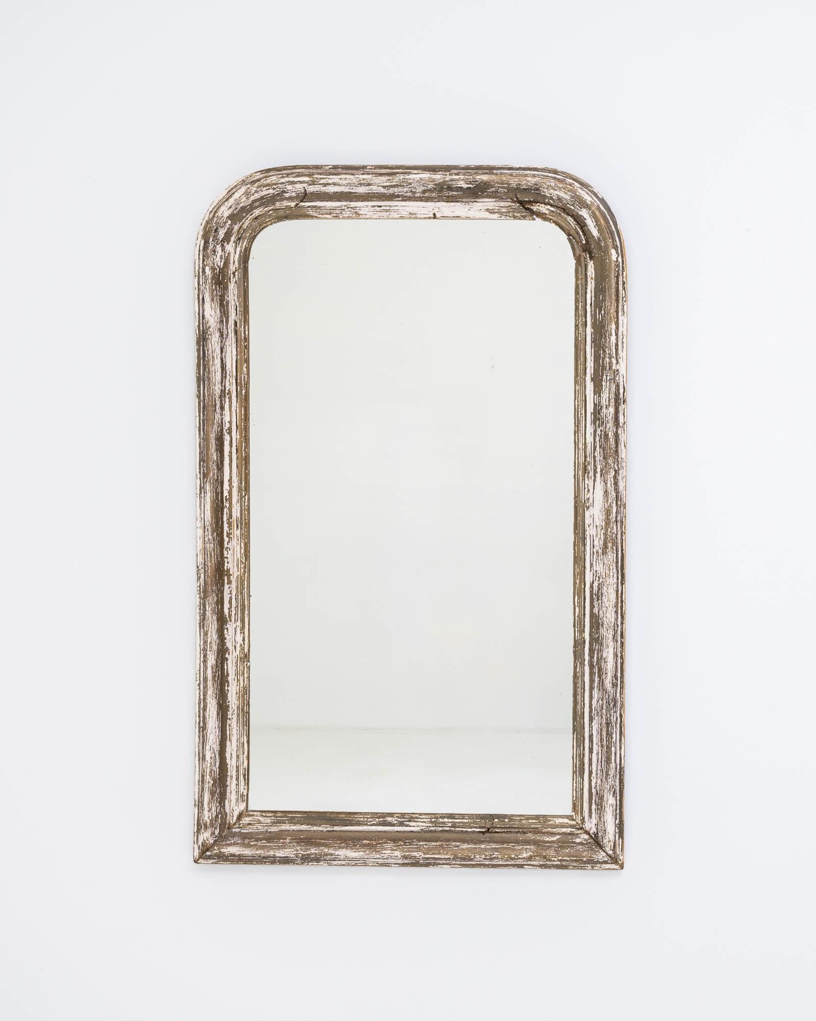 A wooden mirror created in 19th century France. Simple and unassuming, this charming mirror possesses a friendly and rustic demeanor. Through the many years, the off-white paint that coats the frame has slowly ebbed away, creating a fascinating