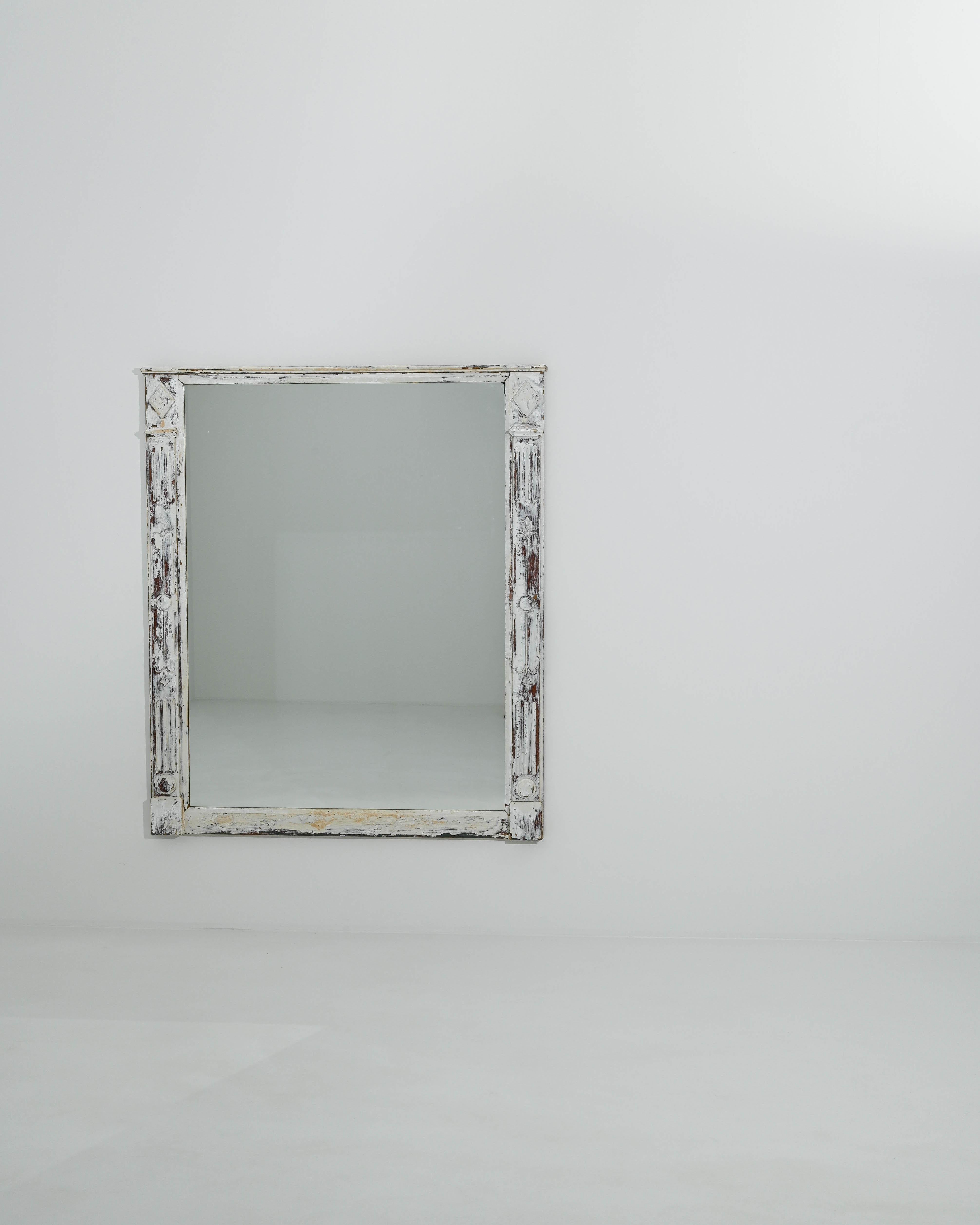 The elegant design and unique patina of this antique wooden mirror give it a timeless appeal. Made in France in the 1800s, the form has a restrained architectural quality. The wide pane of glass is framed by a pair of columns, decorated with fluted