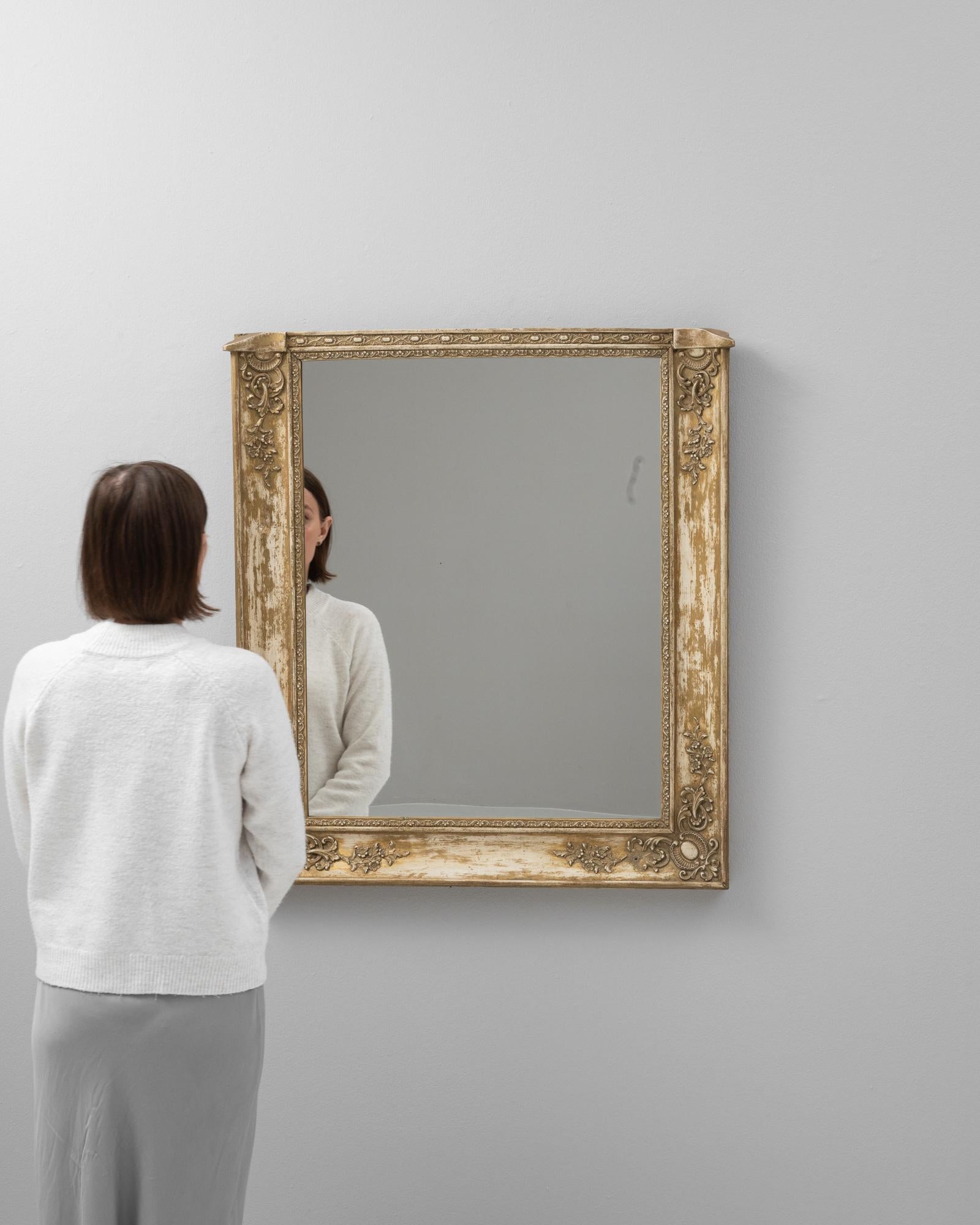 Cet exquis miroir en bois français du XIXe siècle témoigne de la grandeur de son époque. Le cadre du miroir, orné de délicates sculptures dorées, présente le style opulent qui caractérisait l'époque. Les luxueux motifs floraux et de volutes,