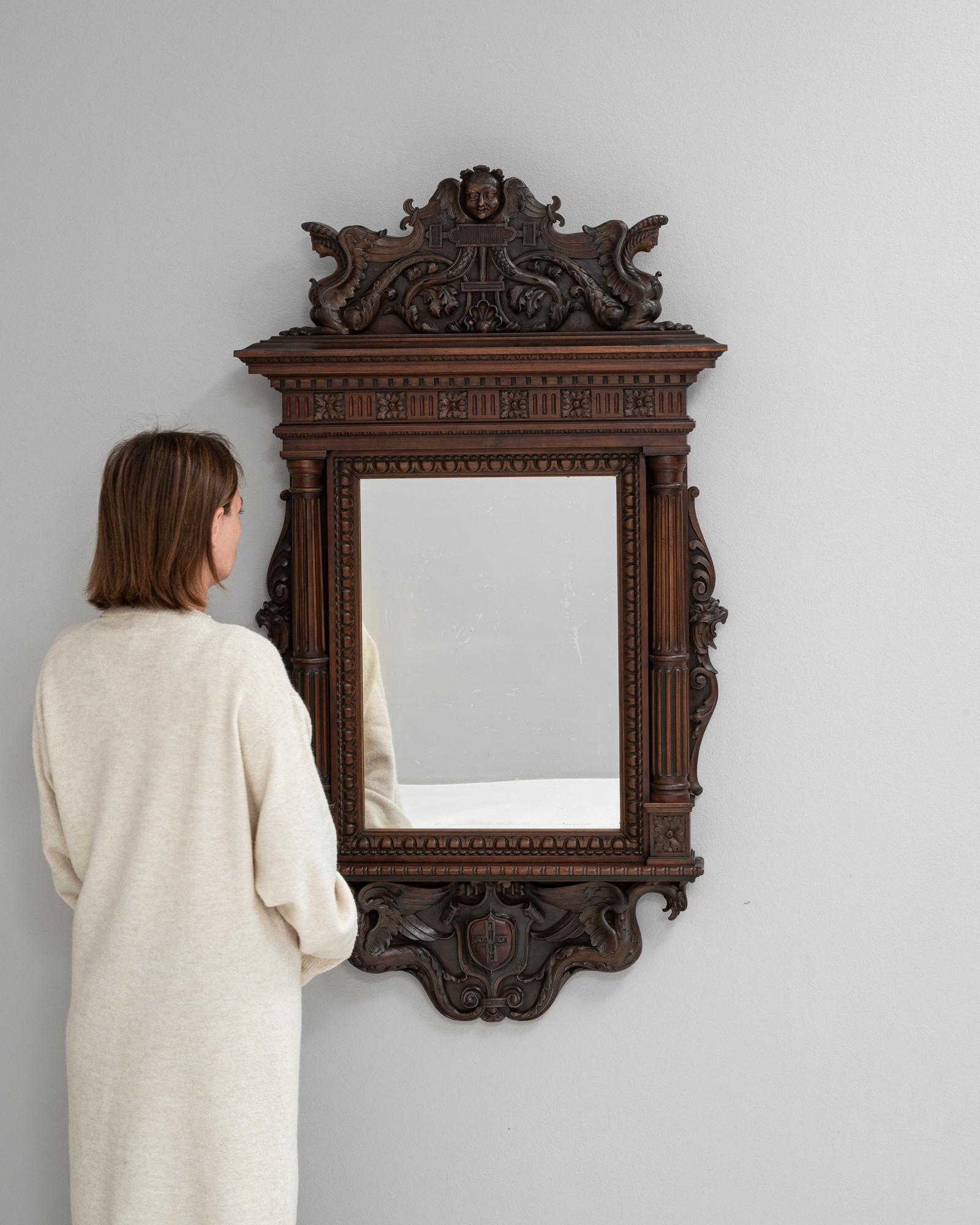 Questo specchio in legno francese del XIX secolo è uno splendido esempio di artigianato antico e di design ornato. Realizzato in legno riccamente intagliato, presenta dettagli intricati, tra cui motivi decorativi ed eleganti volute, che riflettono