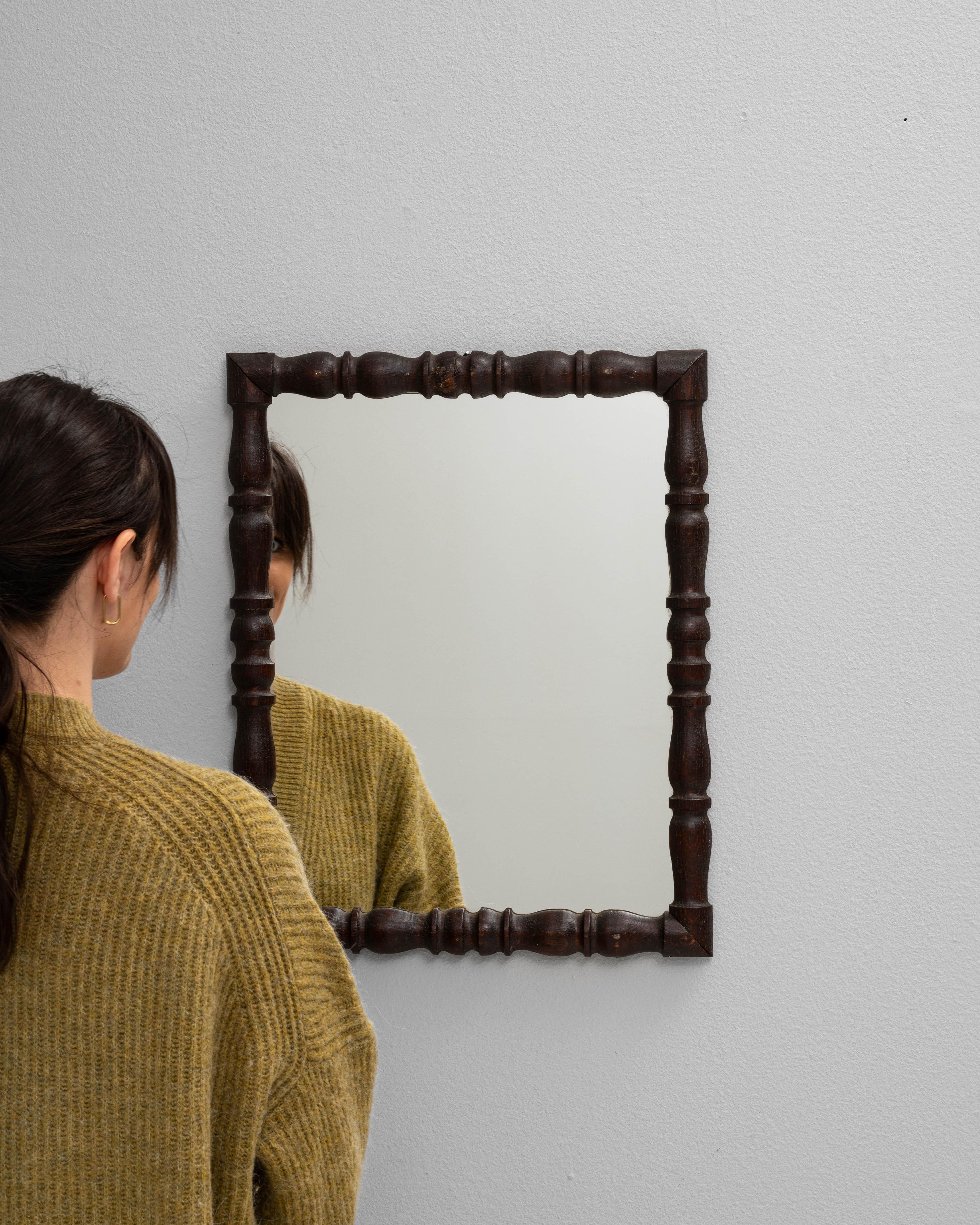 Ce miroir en bois français du XIXe siècle présente un cadre finement tourné avec des détails de fuseaux classiques, ajoutant une ornementation subtile à sa silhouette par ailleurs simple. La finition chaude et foncée met en valeur le grain naturel
