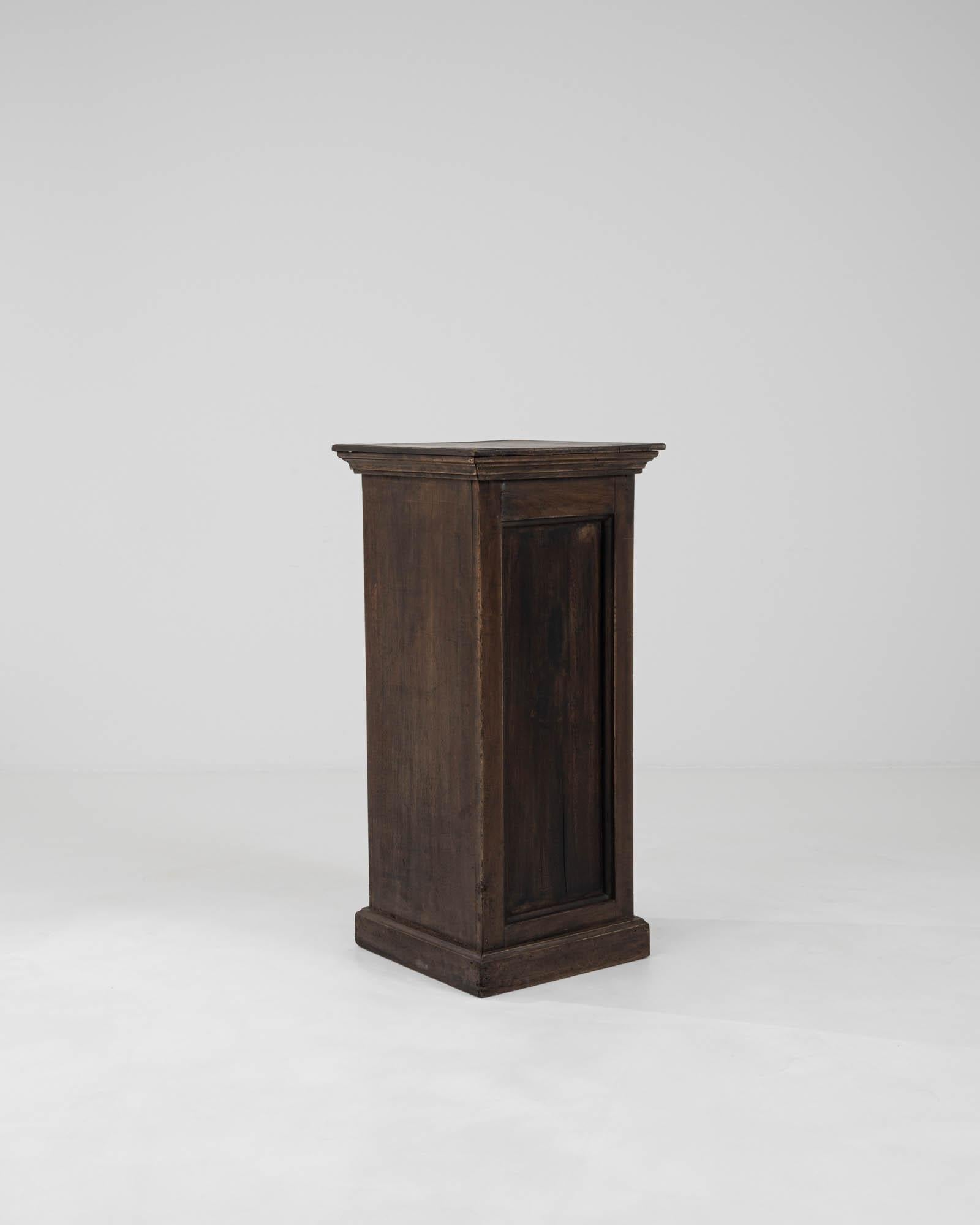This 19th Century French Wooden Pedestal stands as a testament to the timeless elegance of classical design. Crafted from solid wood, its rich, dark patina and sturdy construction echo the durability and charm of a bygone era. With a slender,