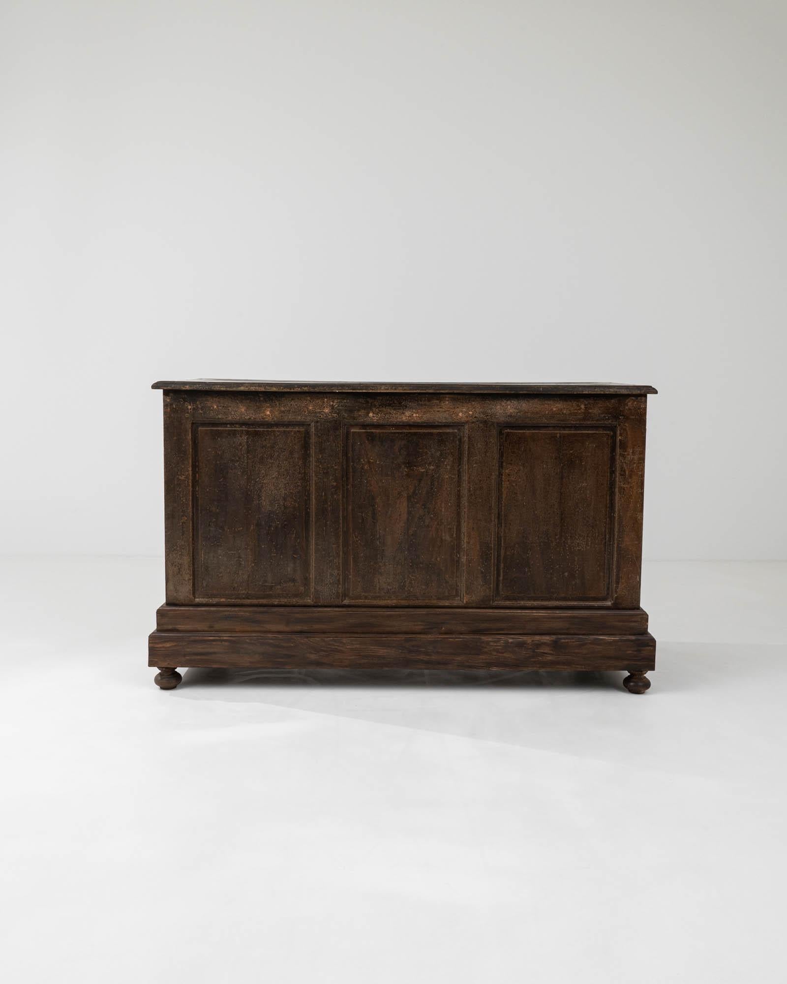 Bearing witness to years of customer interactions, this oak shop counter was crafted in 19th-century France. Its design exudes elegance with intricate profiled panels gracing the front and sides of the bar, along with molded step carvings on the